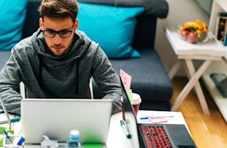 [Featured Image] A man works on a laptop at an office table. 