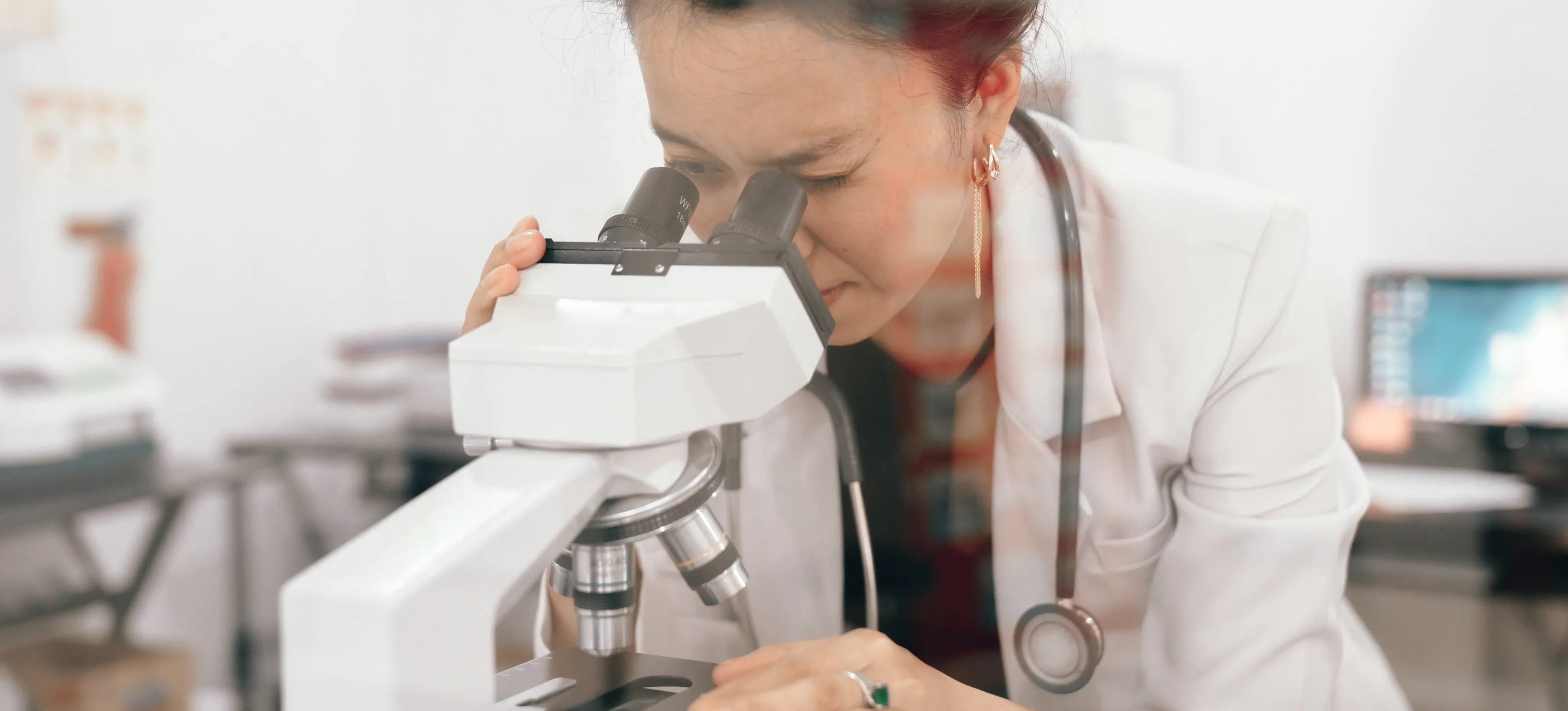[Featured Image] A person who receives a research scientist's salary researches while looking into a microscope in a lab.

