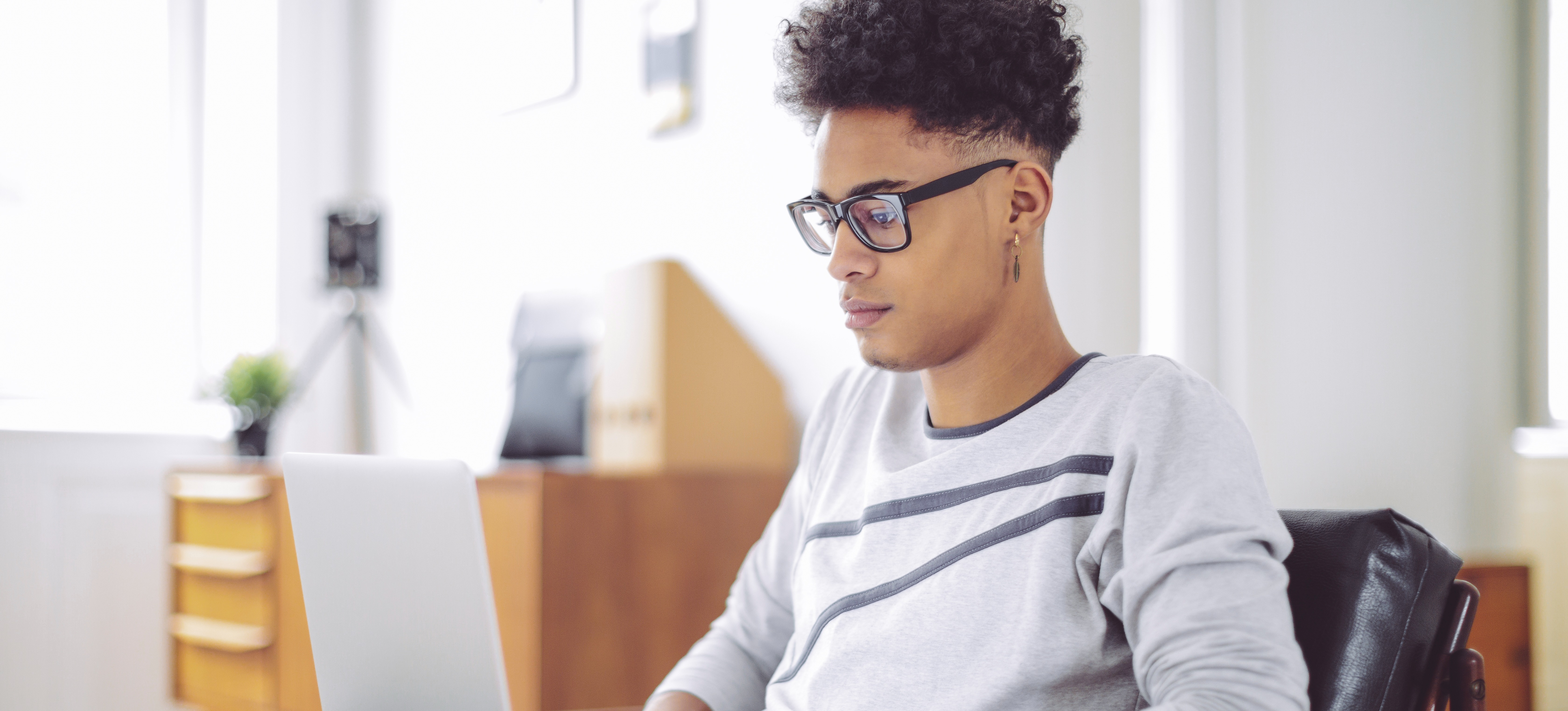 [Featured Image] A young student sits in a chair with a laptop and looks up how to use Bard (now Gemini) for summarizing webpages.
