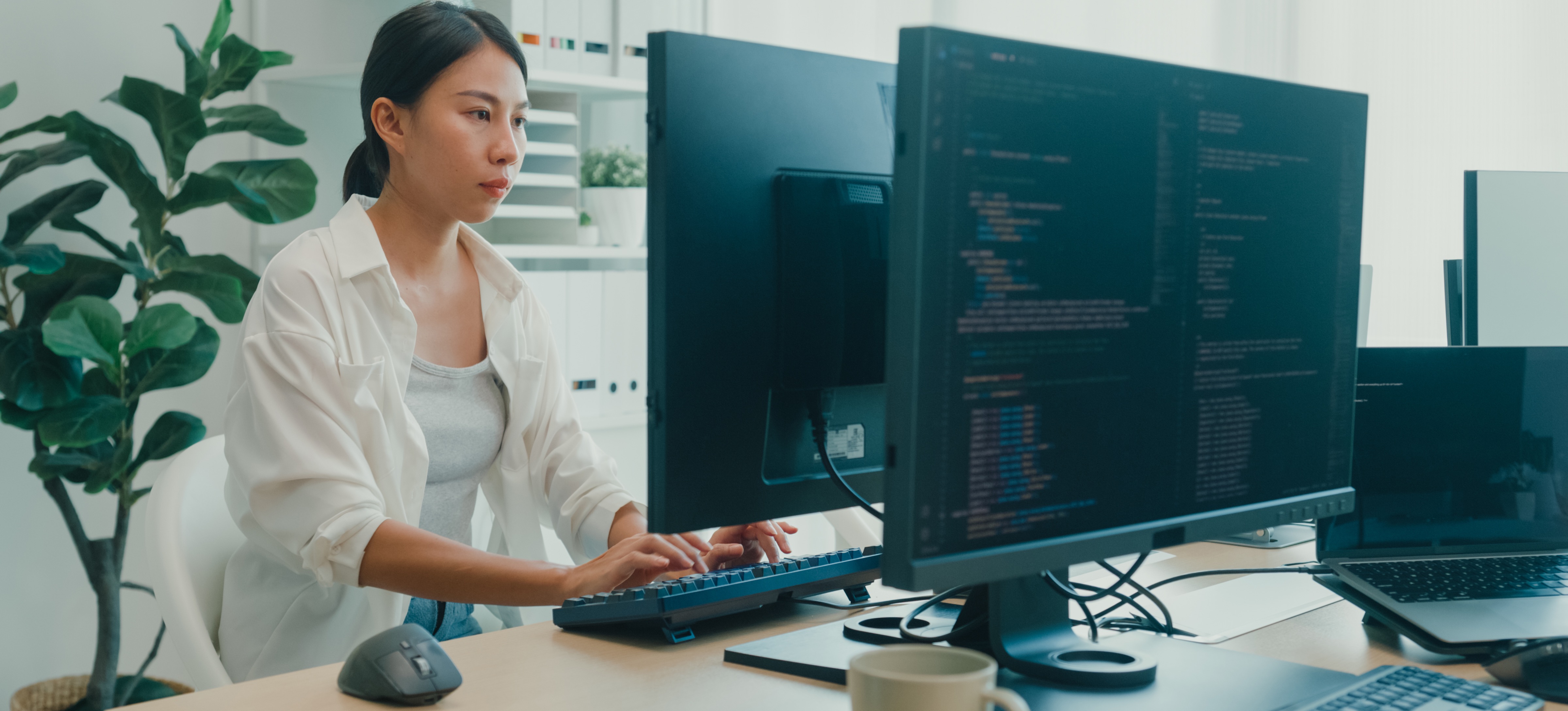 [Featured Image]: A mobile game developer sits at a table, working on their desktop computer.
