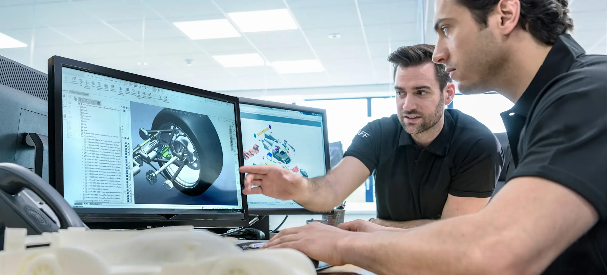 [Featured Image] Two graphic designers use AI graphic design tools as they work on a project featuring a race car.
