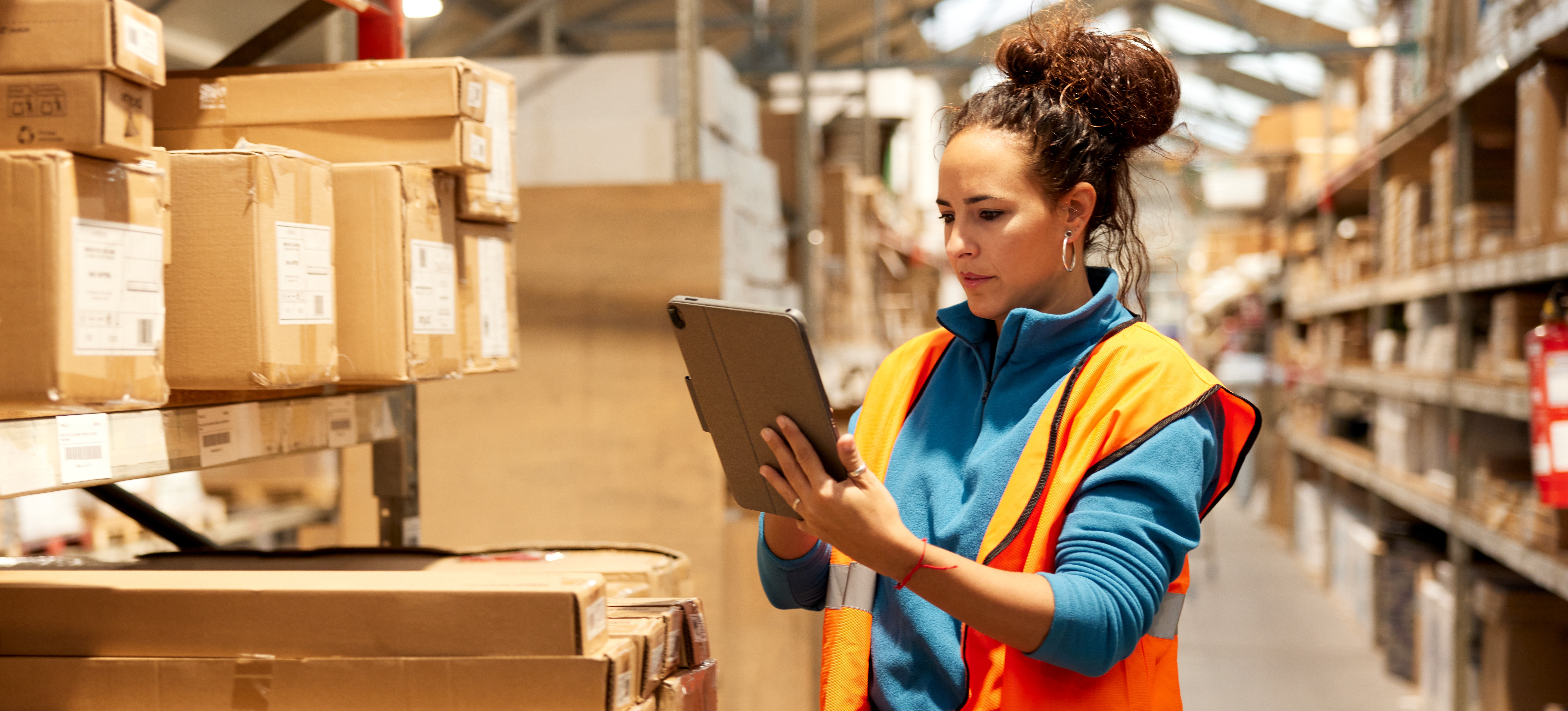 [Featured Image] A warehouse worker takes inventory with the help of digital supply chain data.
