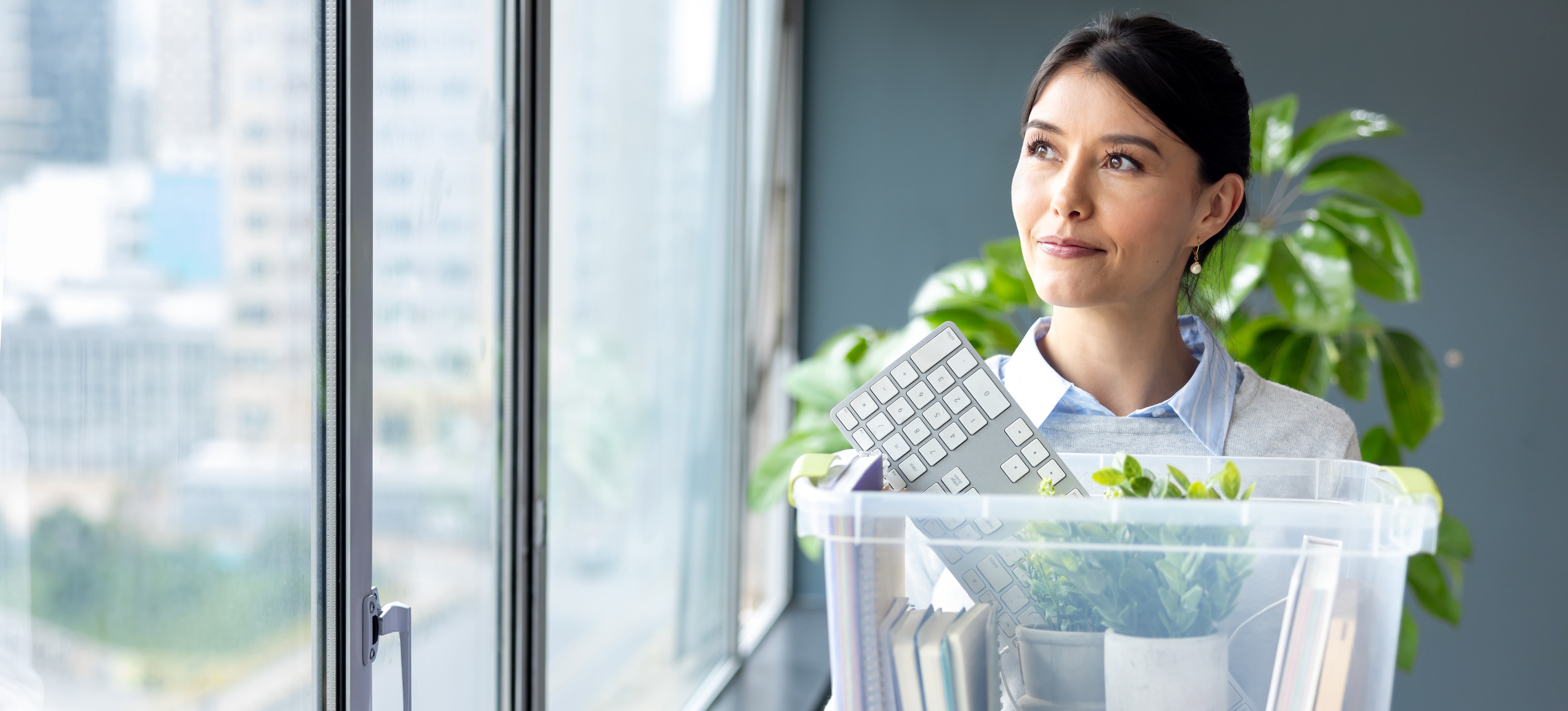 [Hauptbild] Ein zufriedener Mitarbeiter profitiert von der internen Mobilität, da er seine Habseligkeiten in einer durchsichtigen Box transportieren und in sein neues Büro umziehen kann.