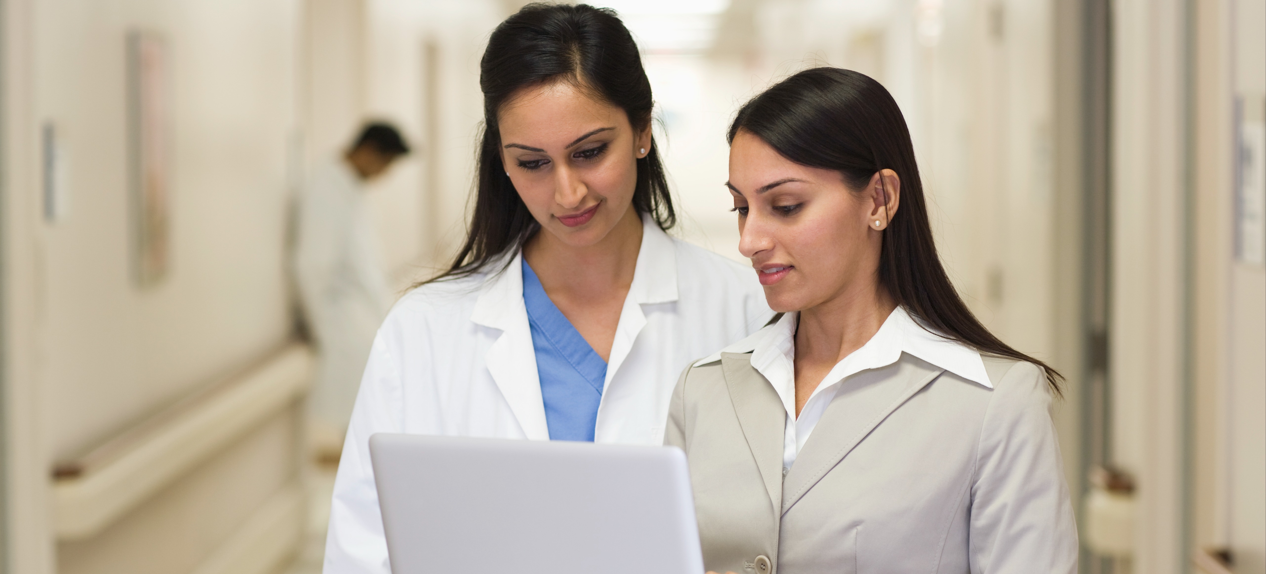 [Image en vedette] Une vendeuse en marketing SaaS présente un programme SaaS à un professionnel de la santé sur un ordinateur portable dans un hôpital.