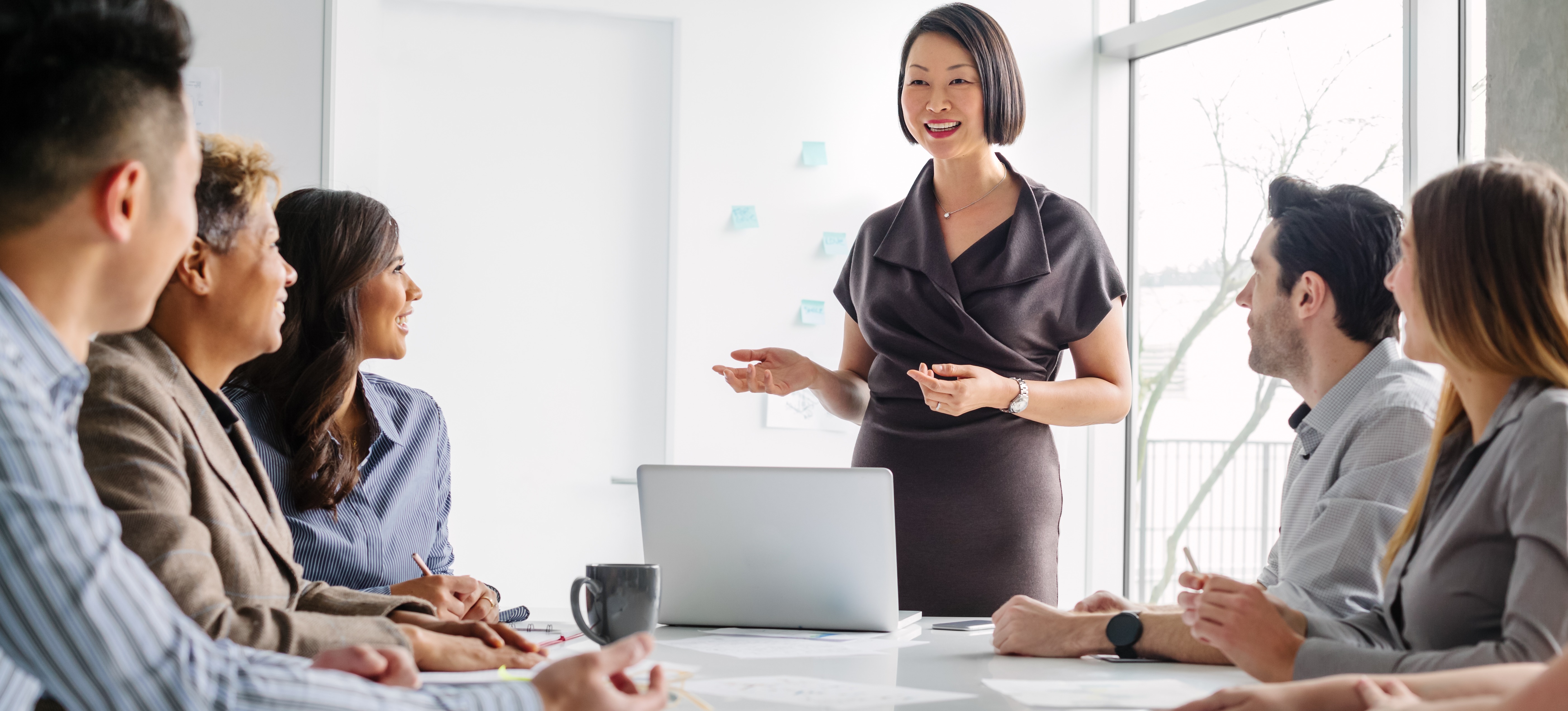 [Featured Image] After learning what is business acumen, a business person addresses their team in a meeting room with greater confidence and success.

