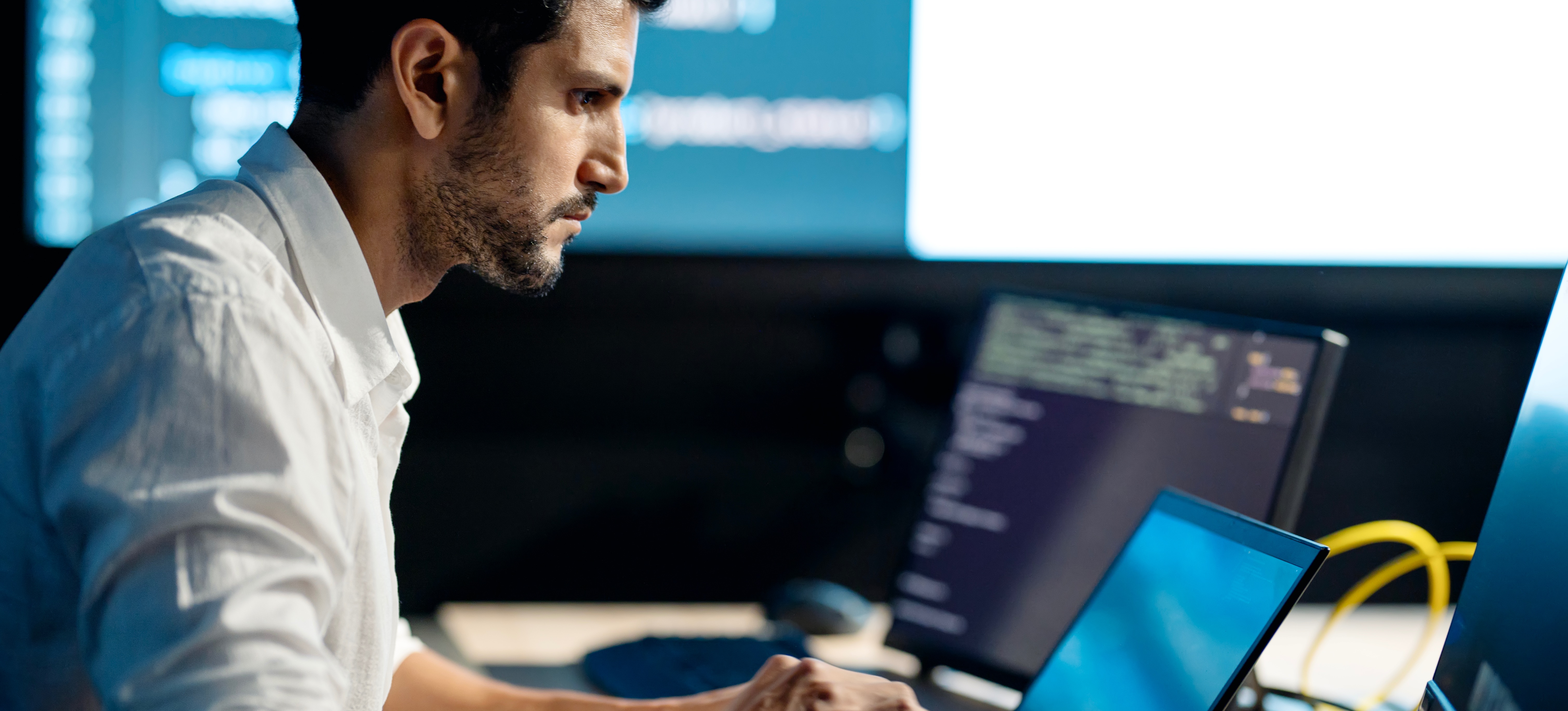 [Featured image]: A machine learning analyst works on a computer with a large screen in the background.
