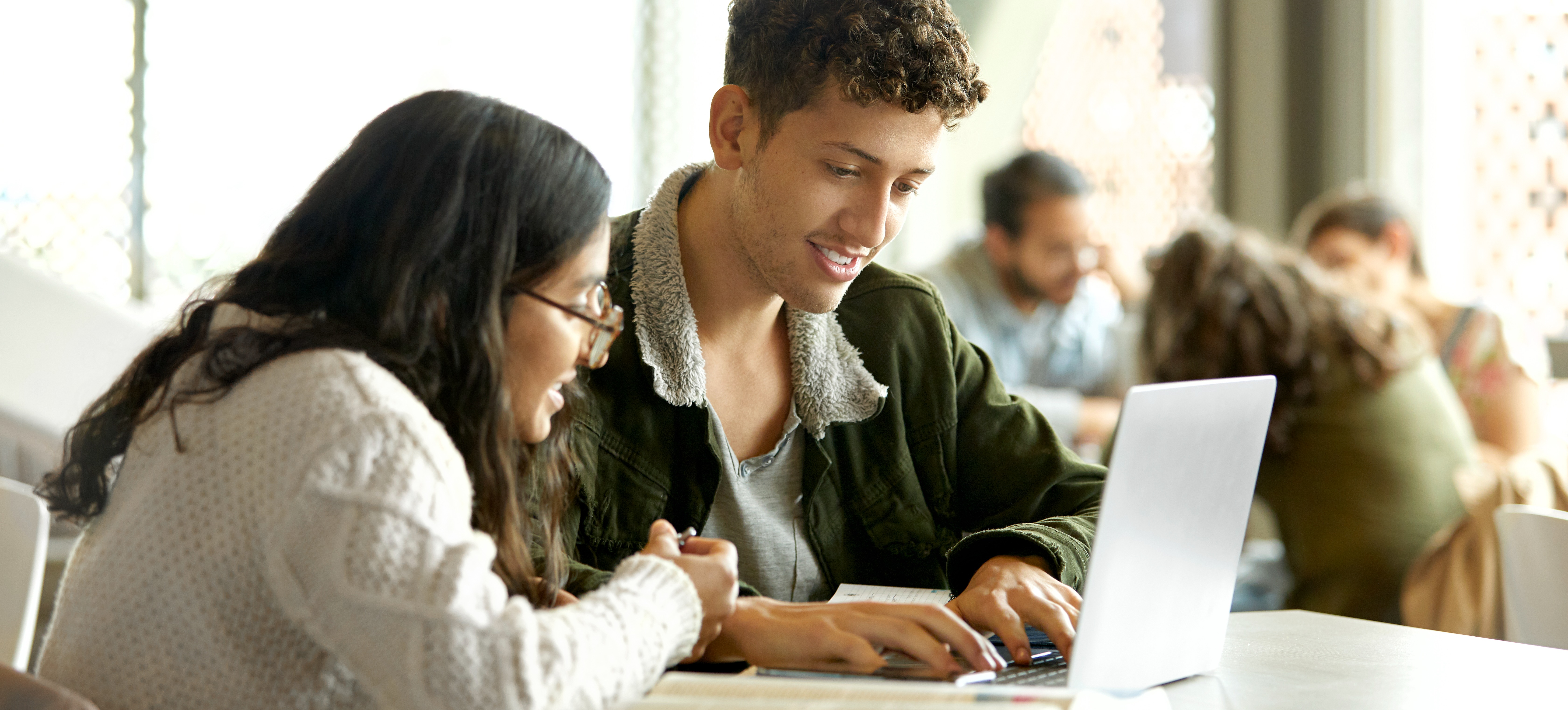 [Feature Image] Two learners in a brightly lit common space research the best way to learn Node.js.