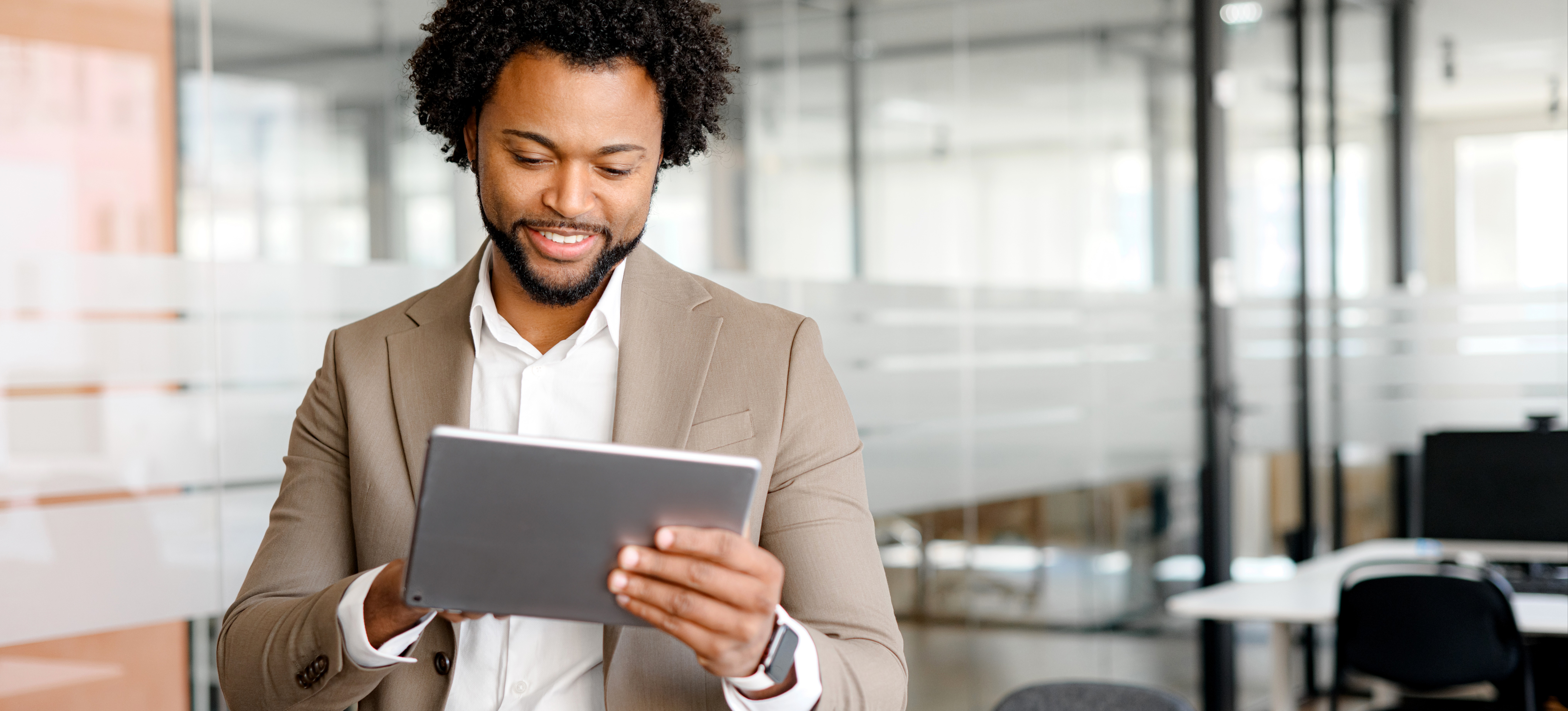 [Featured Image] A confident businessperson in a tan suit and white button-down shirt accesses BI software on their tablet to help find data-driven solutions to overcome a business challenge.
