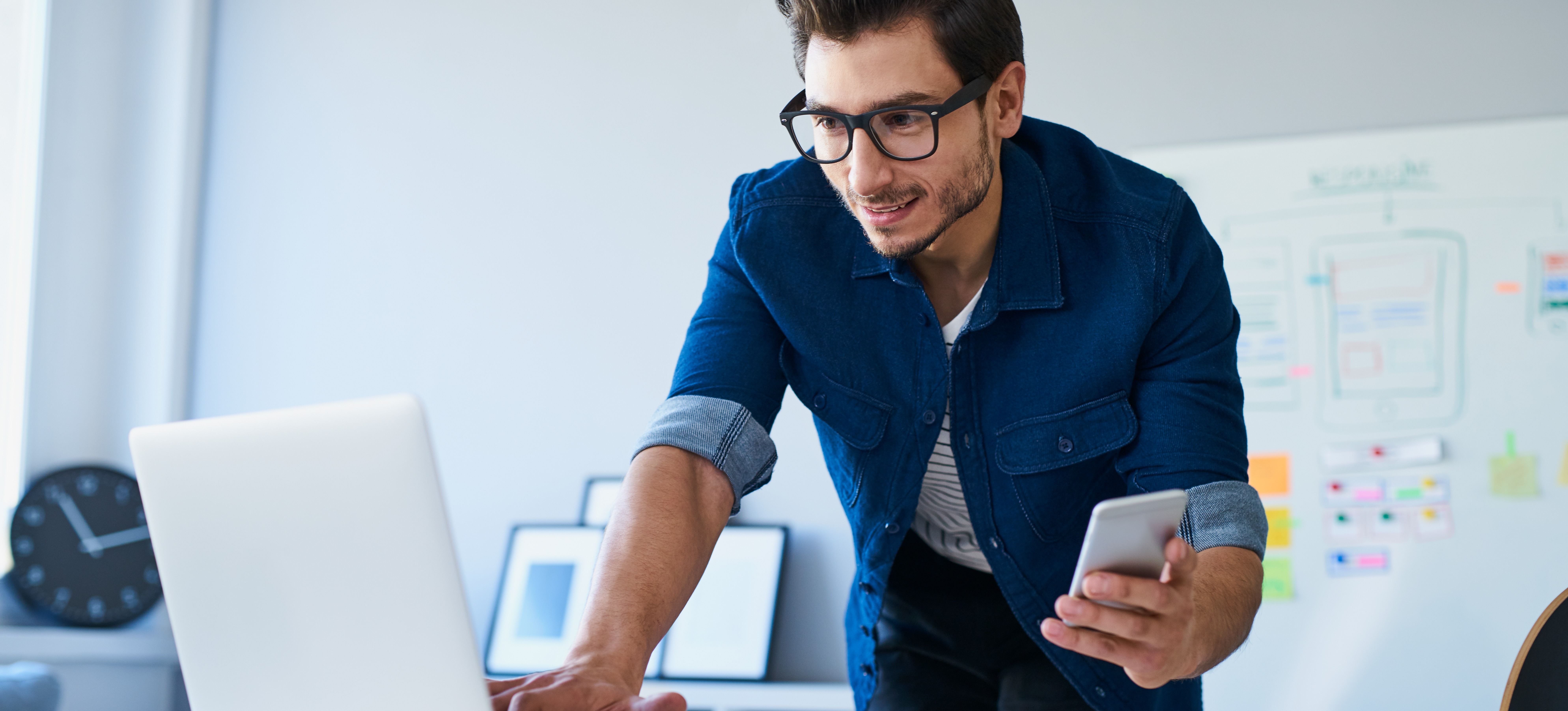[Featured image] An Android app developer in a blue shirt works with a laptop and a smartphone. 