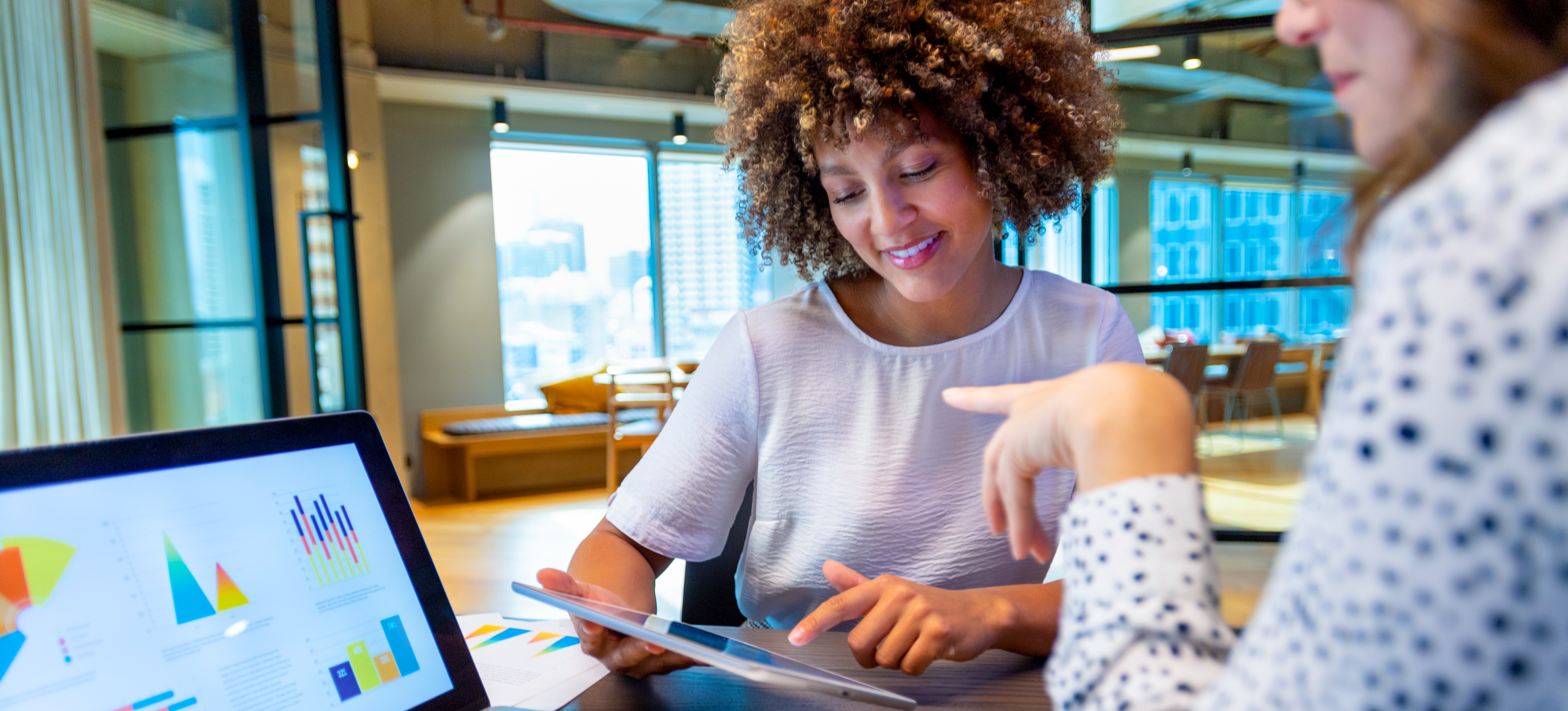 [Featured Image] A learner asks, “What is an attention mechanism?” and gets details from their mentor as they discuss data analysis in a workplace environment with a computer displaying data.
