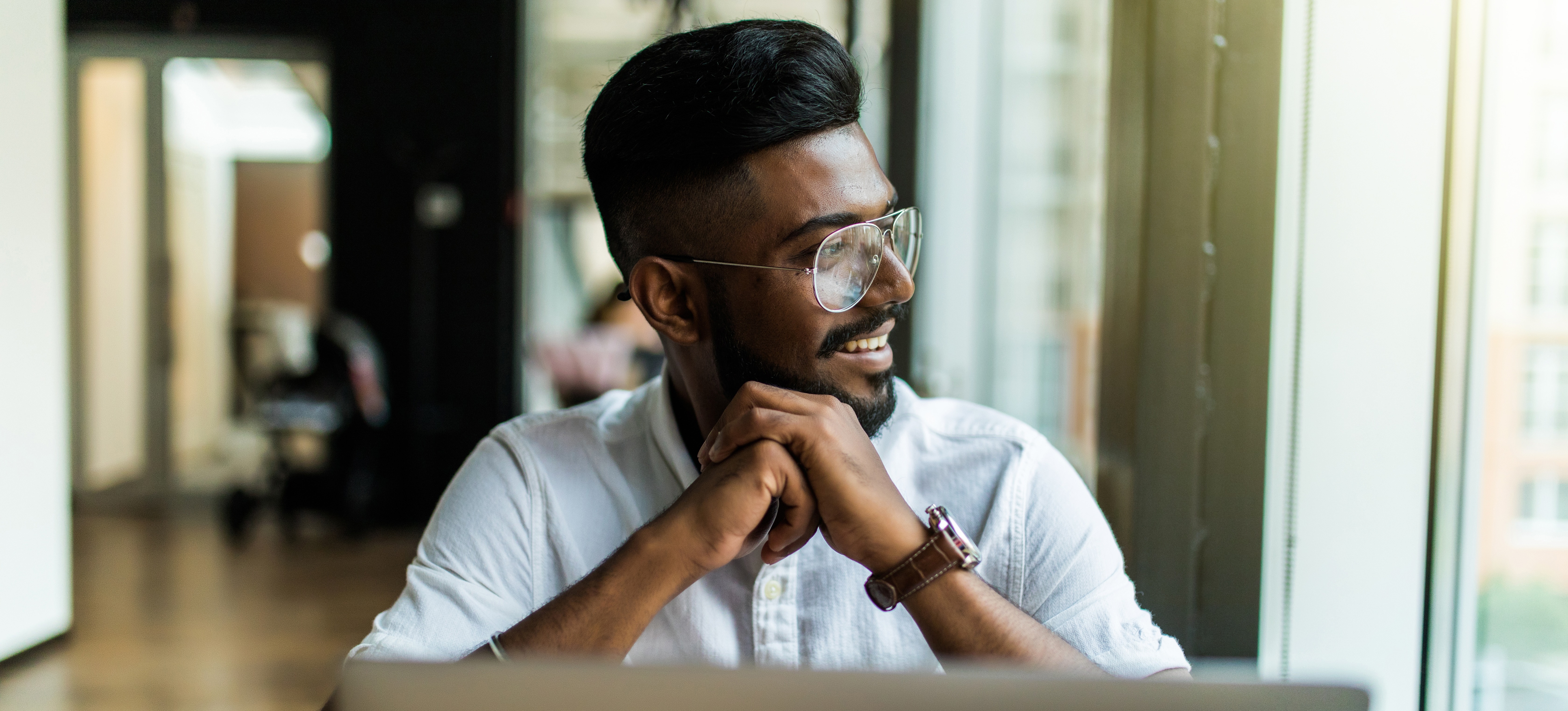 [Featured Image]: A man sits in front of a laptop contemplating the differences between IaaS, PaaS, and SaaS used in cloud computing.
