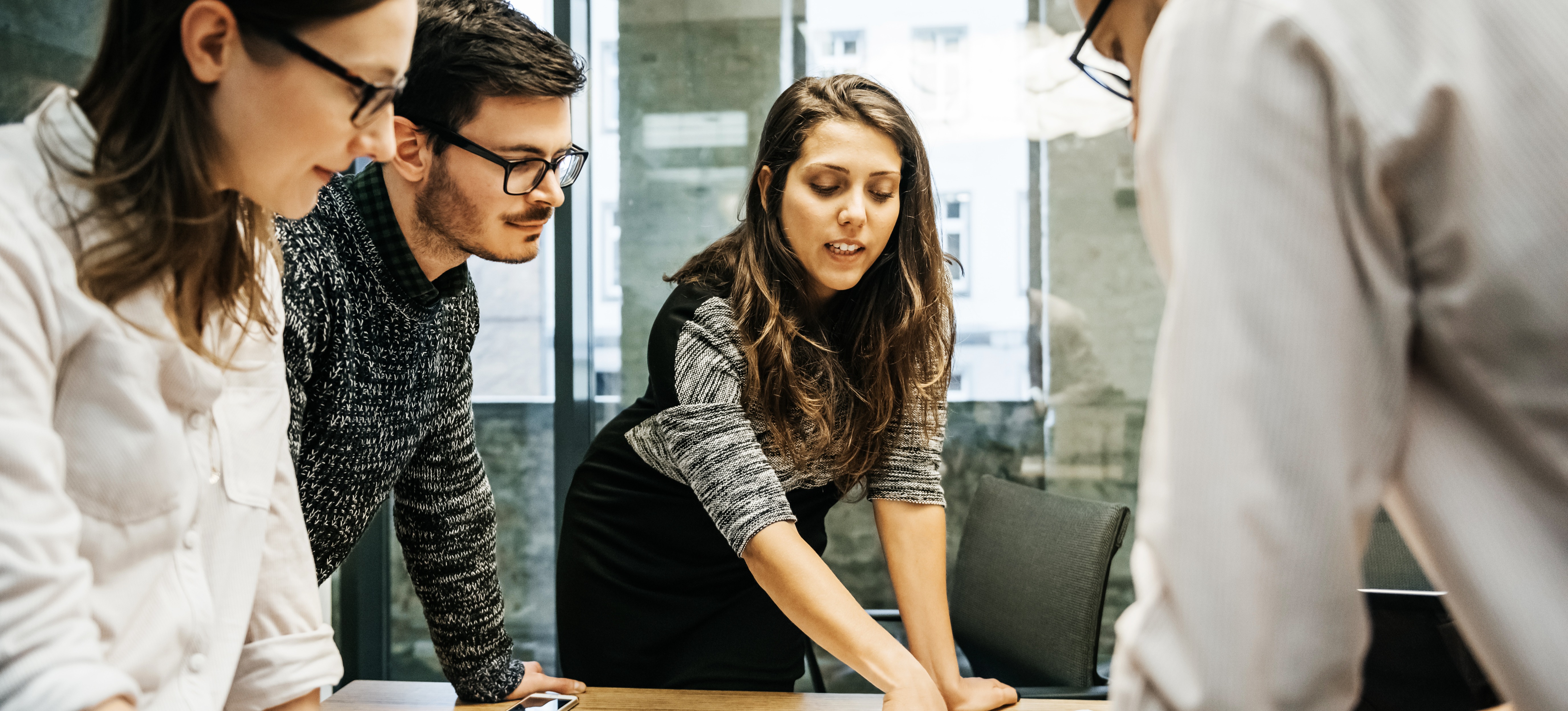 [Image en vedette] Un groupe de quatre professionnels, deux hommes et deux femmes, discutent de la manière d'améliorer les opérations au sein de leur entreprise en utilisant le cycle planifier-faire-vérifier-agir.