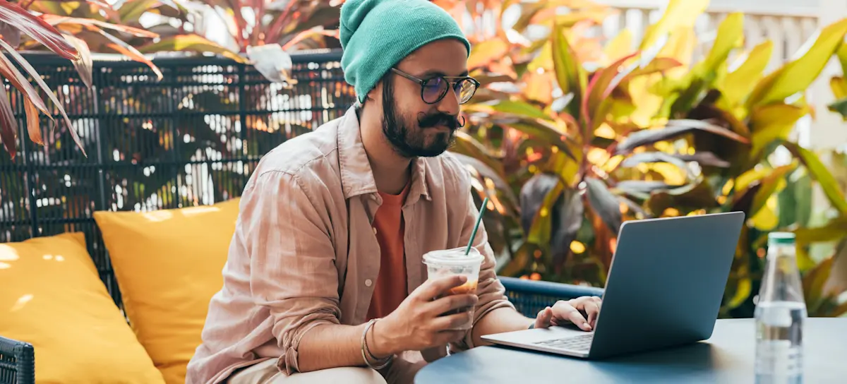 [Featured Image] A cloud computing professional sits at an outdoor table with a laptop, working remotely.
