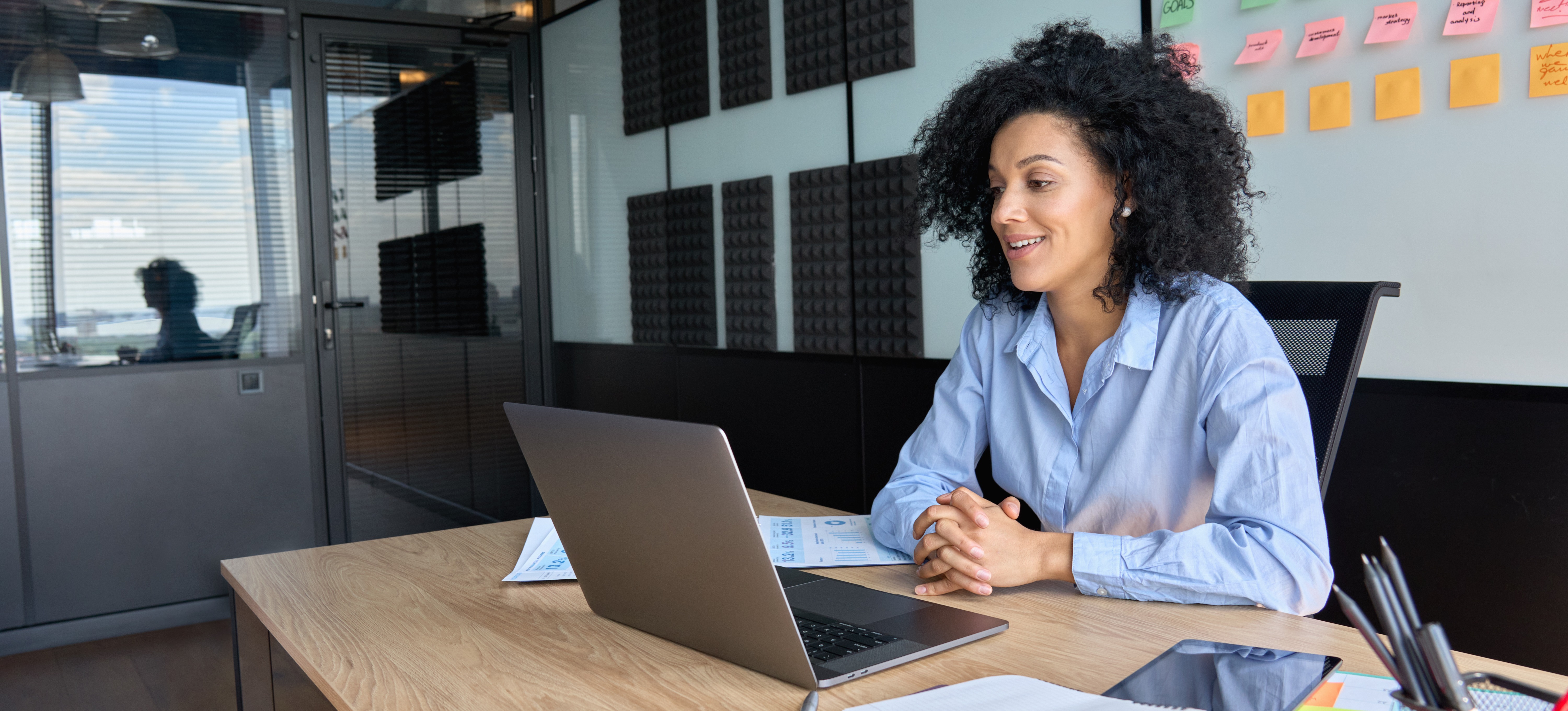 [Featured Image] An email marketing specialist sits at their desk in her office, looking at their laptop to participate in a video meeting with colleagues. 

