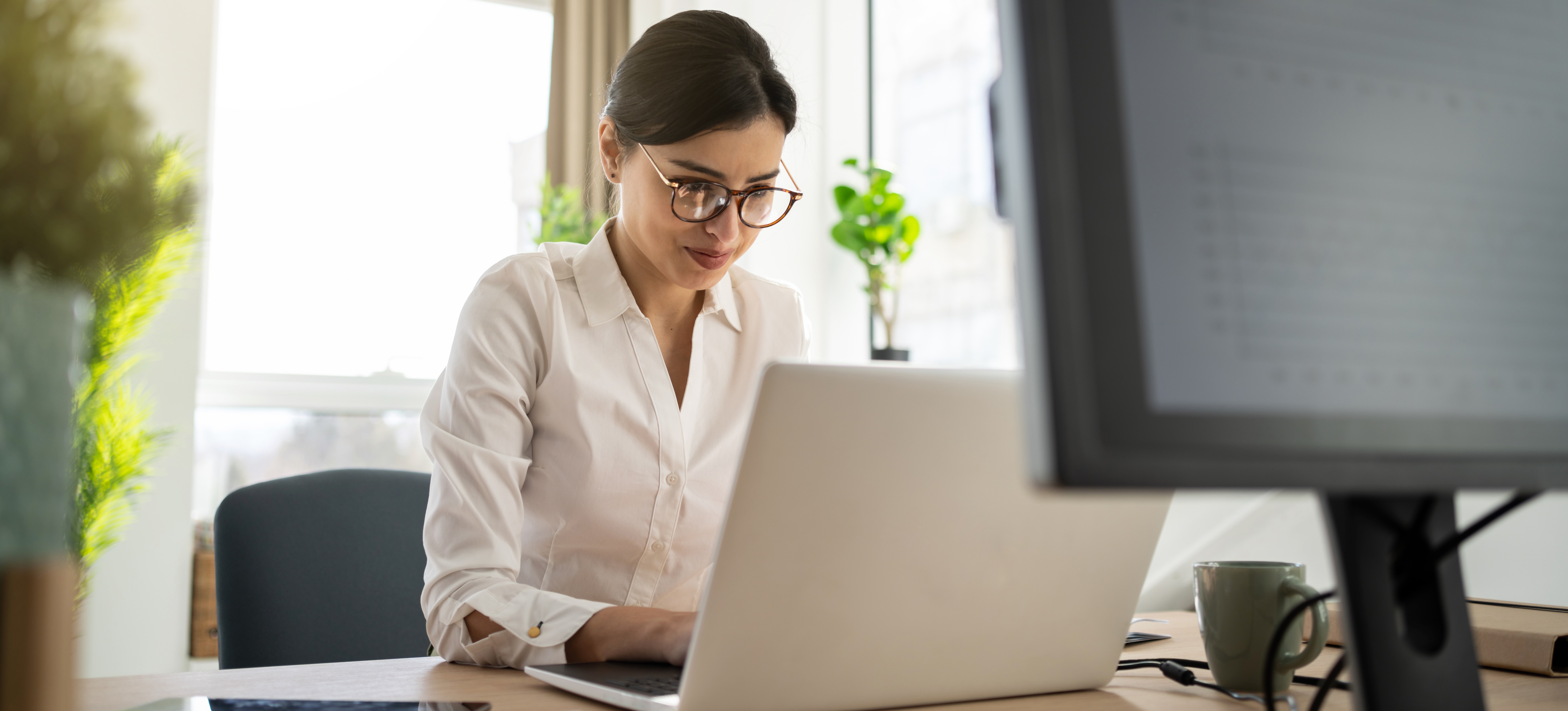 [Featured Image] A Certified Business Analyst Professional holder sits in her office contemplating as she works on her laptop.
