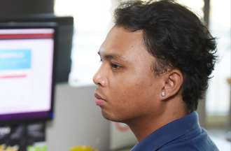 [Featured Image]:  A college student,  wearing a blue shirt and working on a desktop computer, using tools to improve memory. 