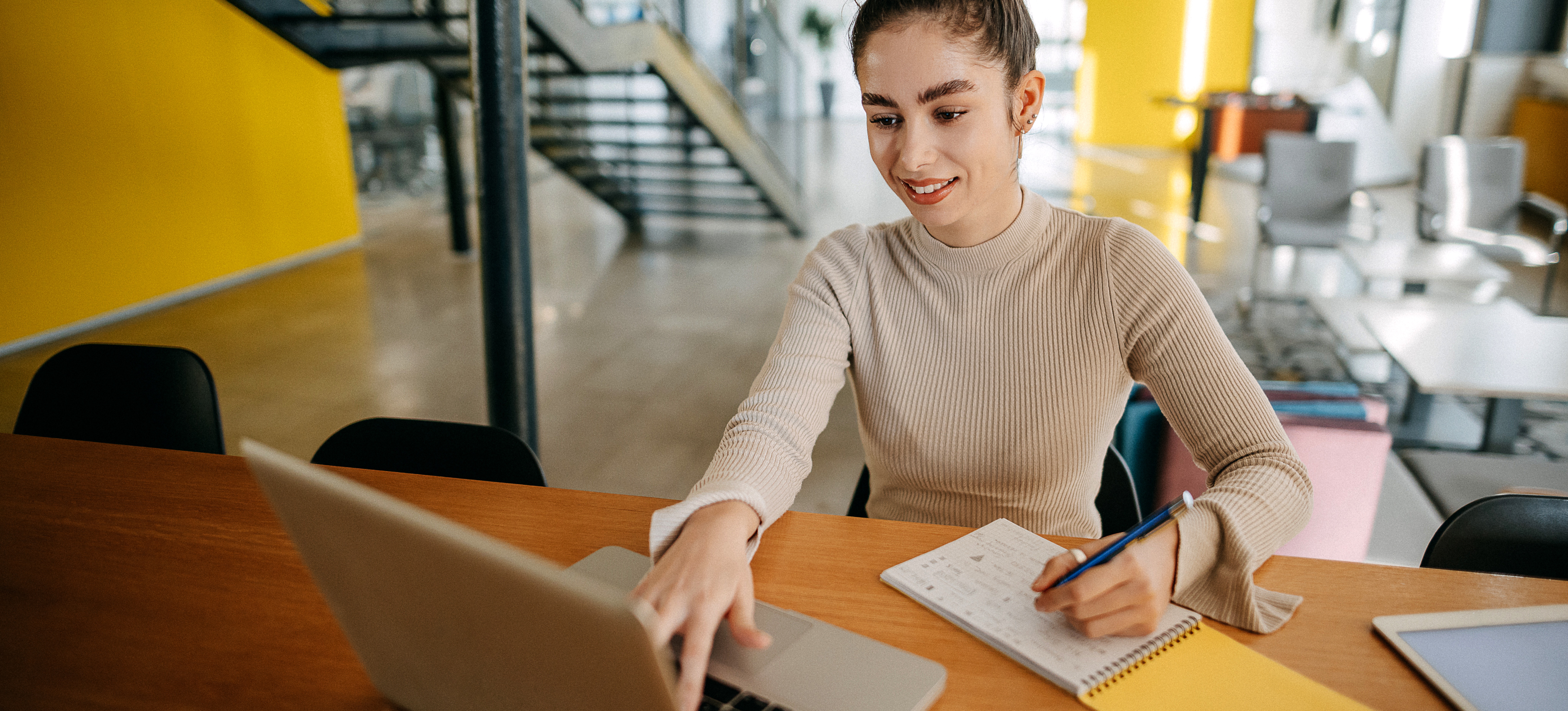 [Featured Image]: A student sits in a study space with a laptop and notebook, preparing for a master’s in finance degree.
