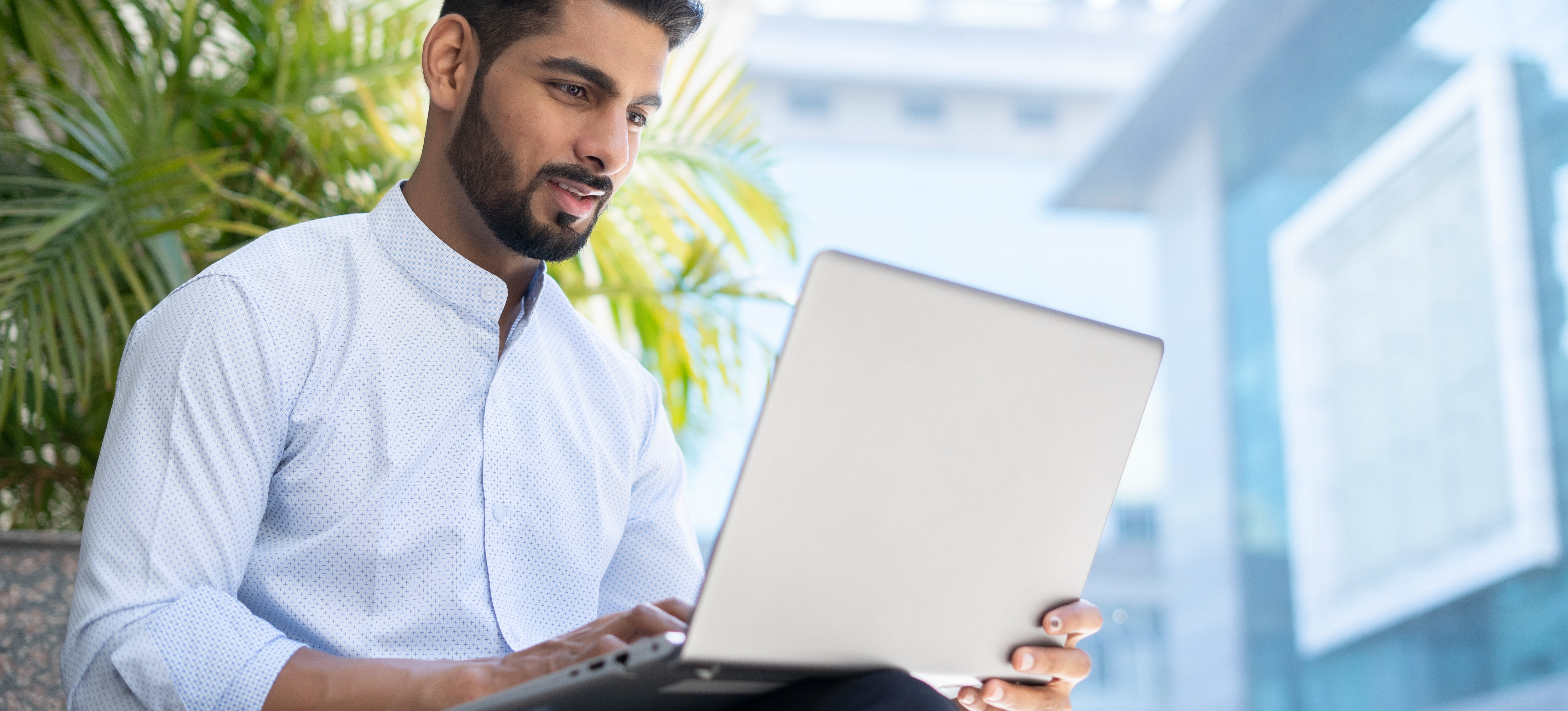 [Featured Image] An Indian small business owner follows some bookkeeping tips as he sits outside and works on his laptop.
