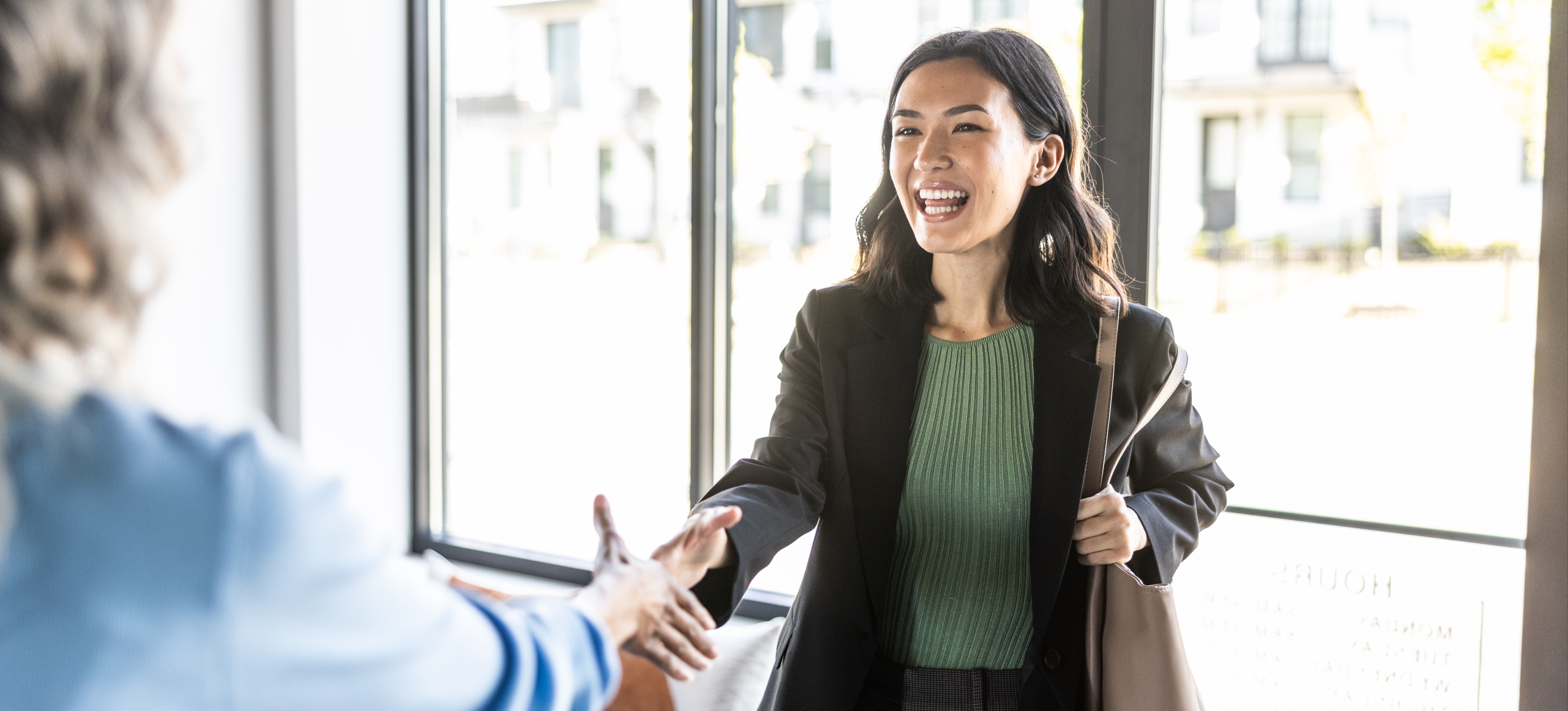 [Featured image] A smiling professional happily shakes the hand of their new employer after getting their first job.
