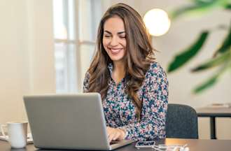 [Featured Image] A process automation specialist sits at her desk with a laptop and develops new software to improve her organization's operations. 
