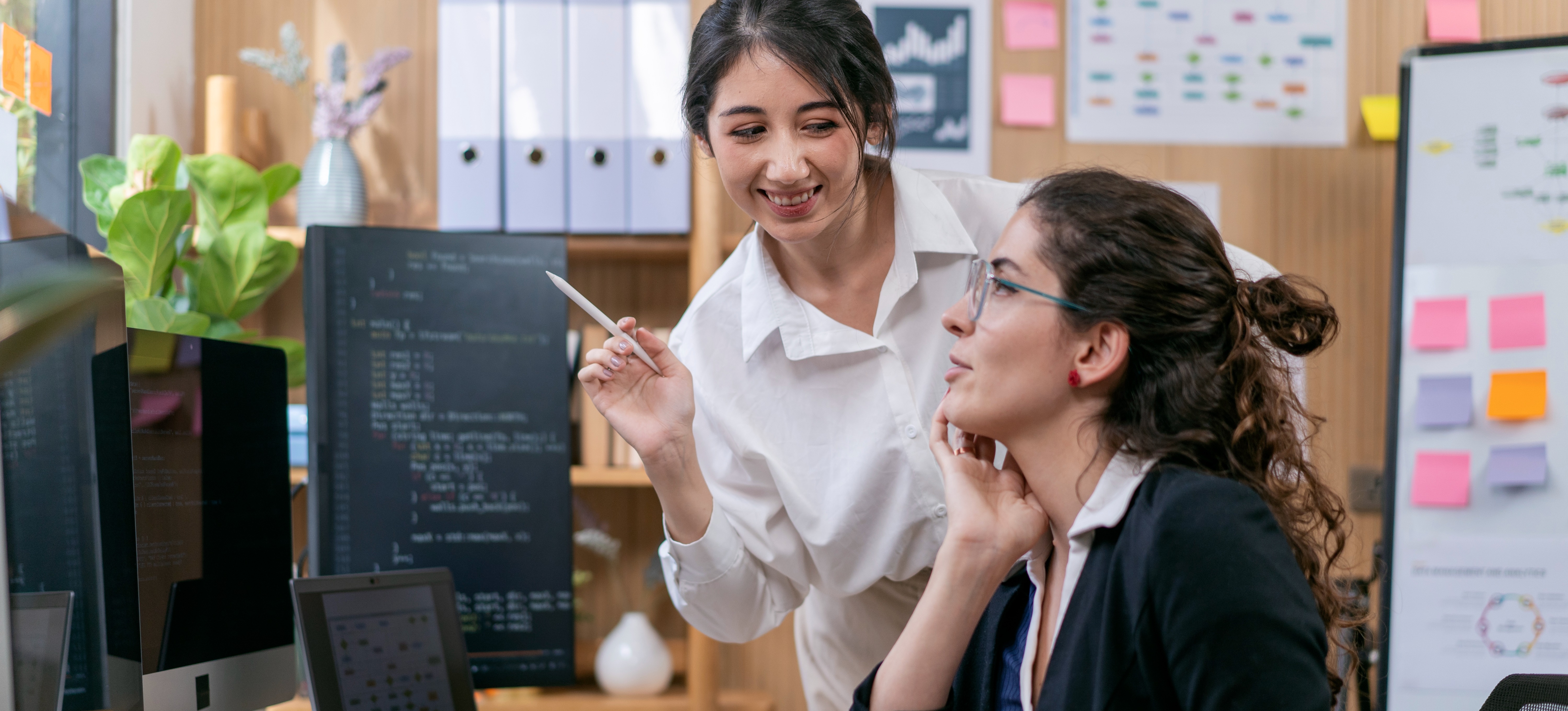 [Featured Image] Software engineers discussing the differences between Edge AI and Cloud AI in a collaborative office environment while using computers.
