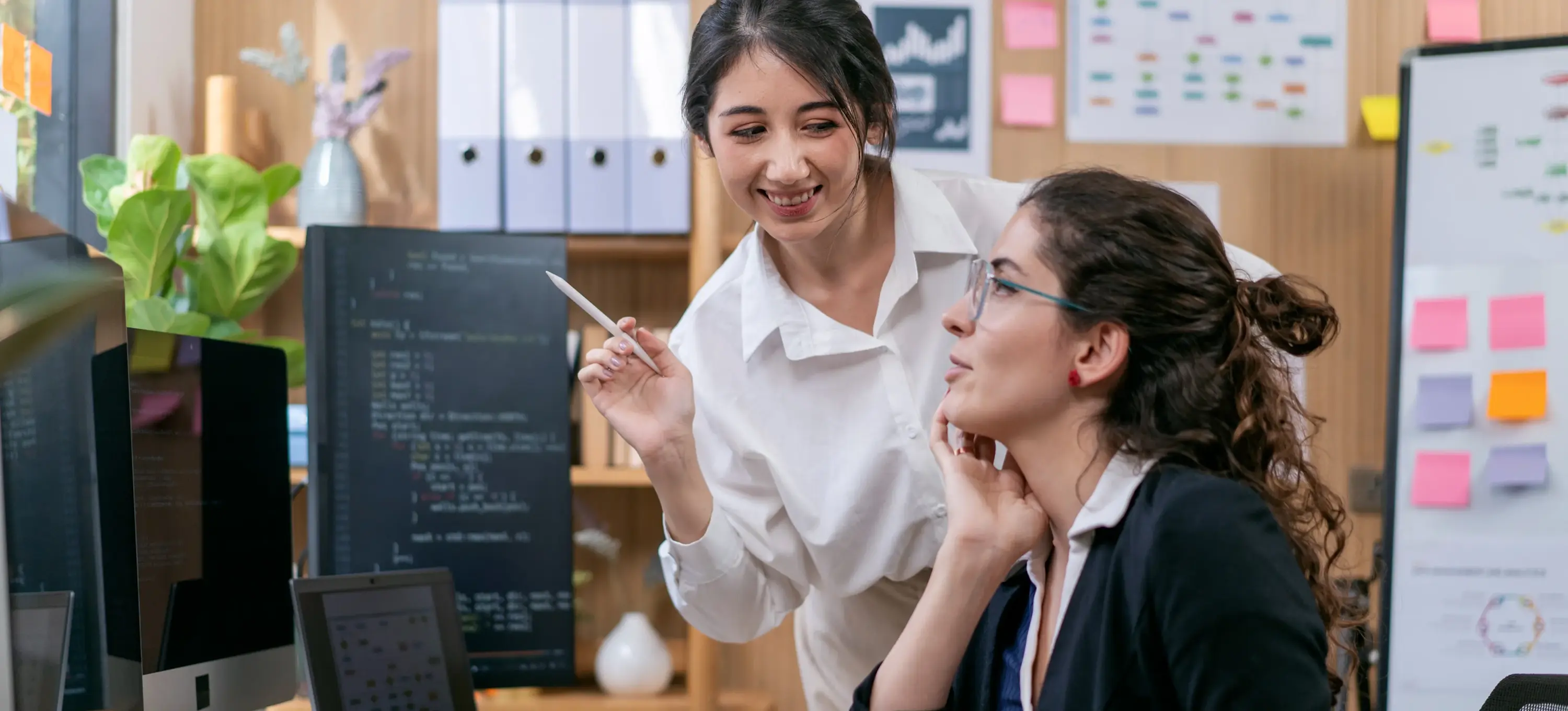 [Featured Image] Software engineers discussing the differences between Edge AI and Cloud AI in a collaborative office environment while using computers.
