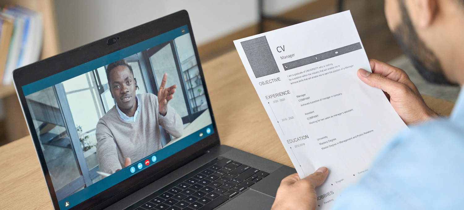 [Featured image] An infographic cover letter sits in the foreground, held by an interviewer. In the background, a person appears on a laptop screen in a Zoom interview.