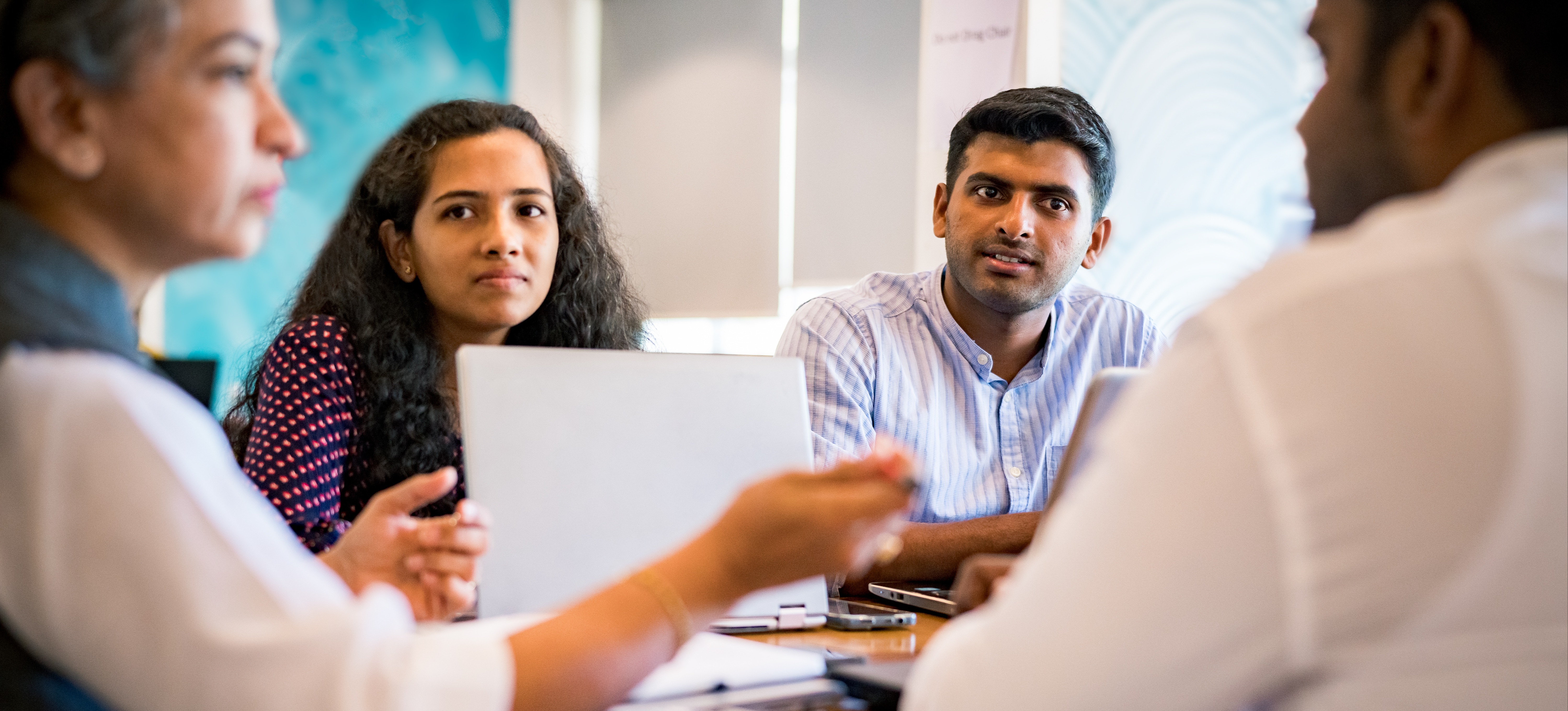 [Featured Image] A group of Indian professionals talking about the MBA entrance exam at a corporate office.
