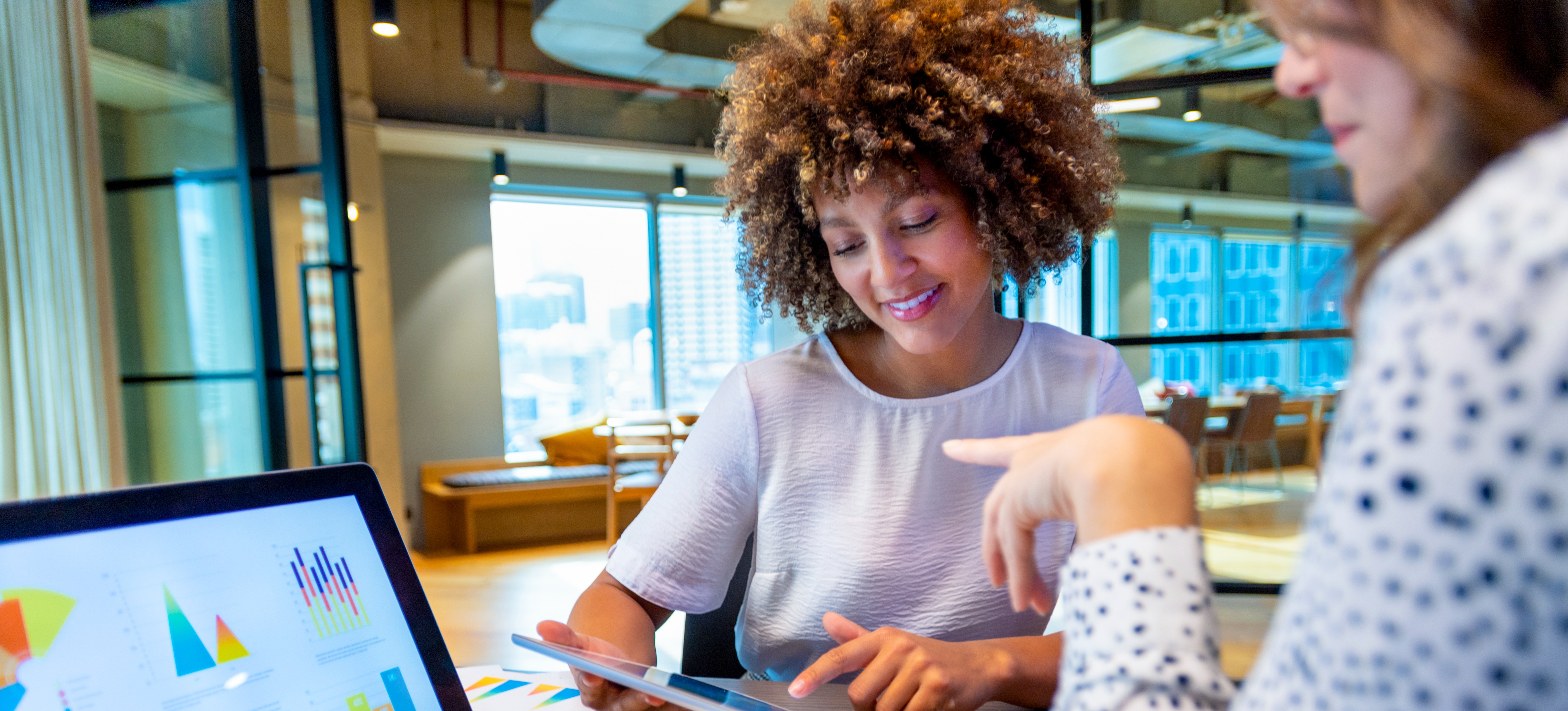 [Featured Image] Two female colleagues are meeting about the data-driven marketing findings for their business.