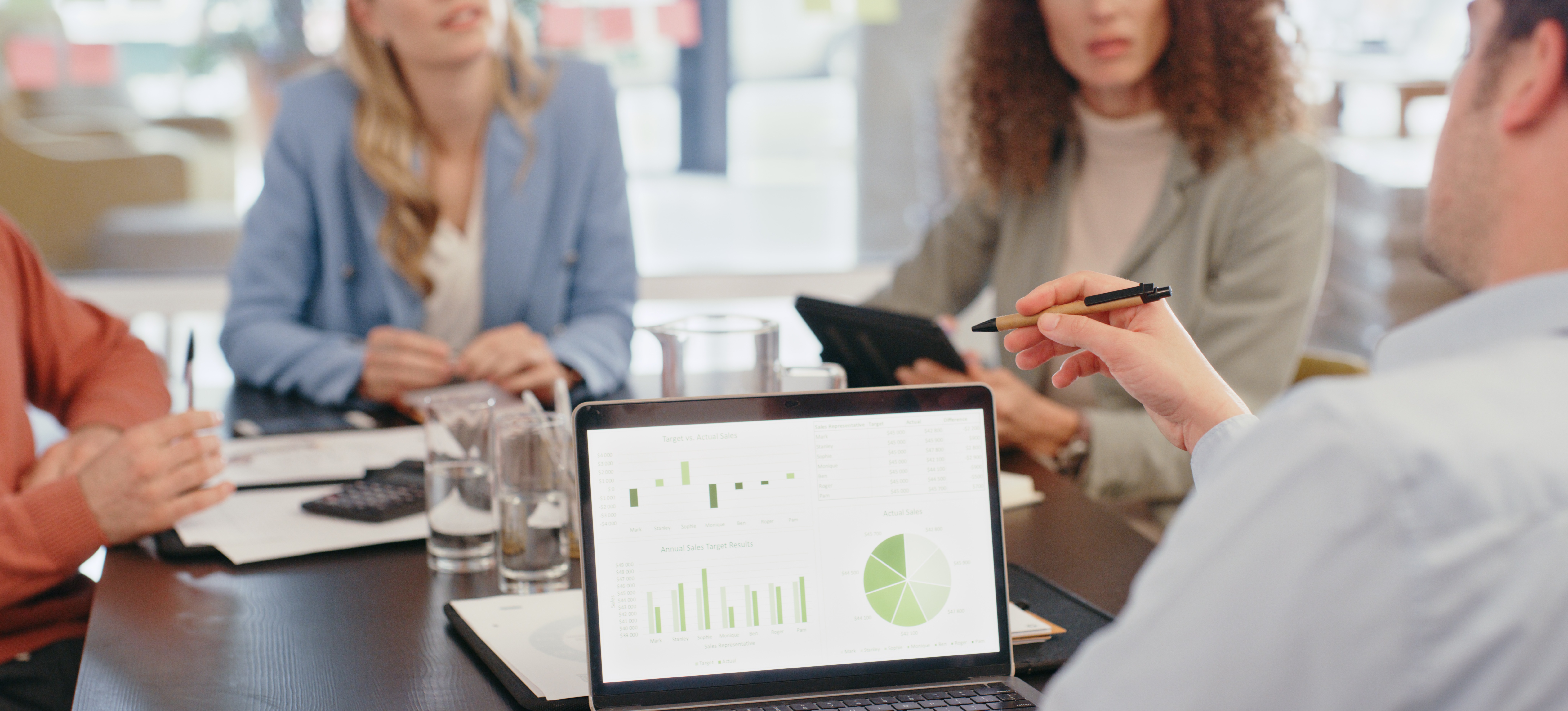 [Featured Image] A group of businesspeople meets to discuss data-driven insights that inform their marketing research, one of the essential big data applications in 2024.
