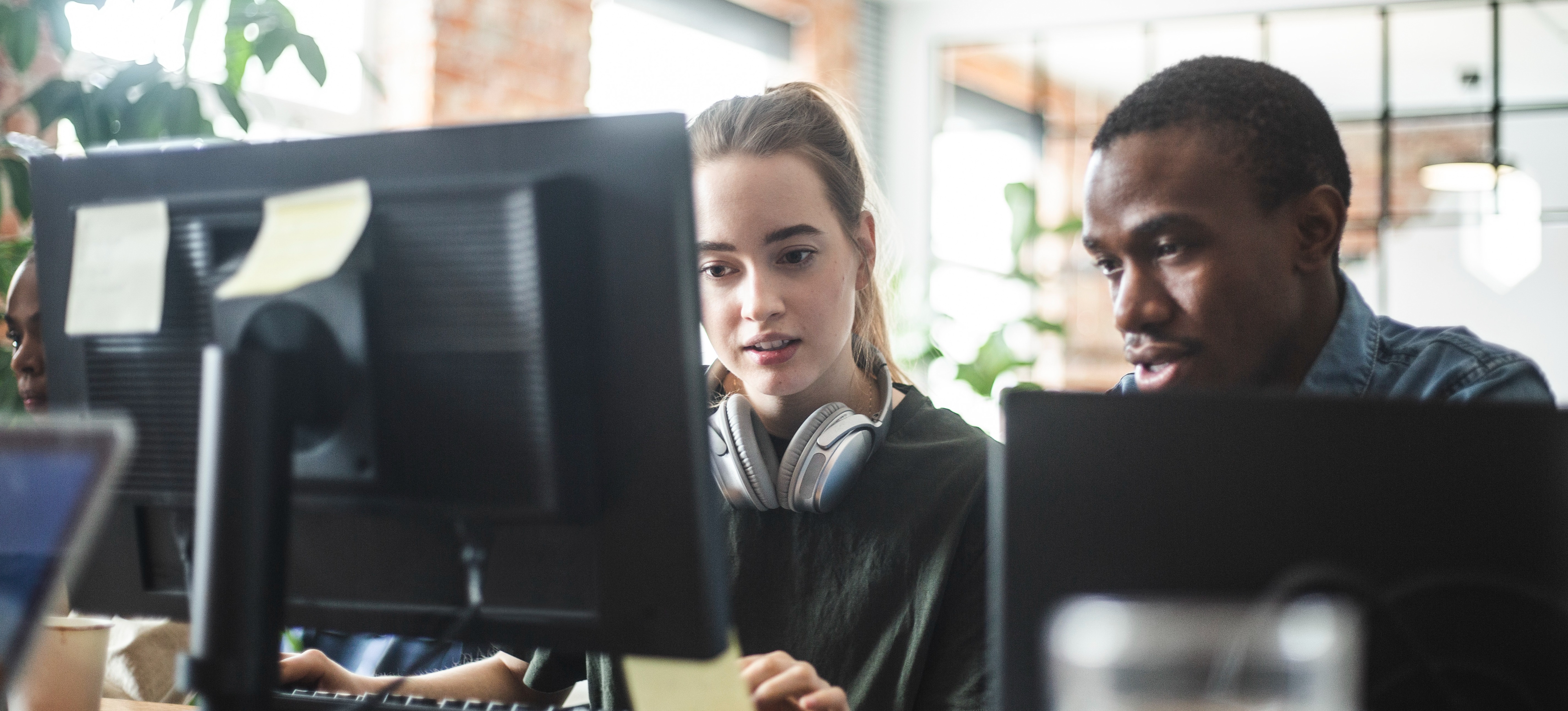 [Featured Image] Two software programmers engage in test-driven development as they sit in front of computer screens.