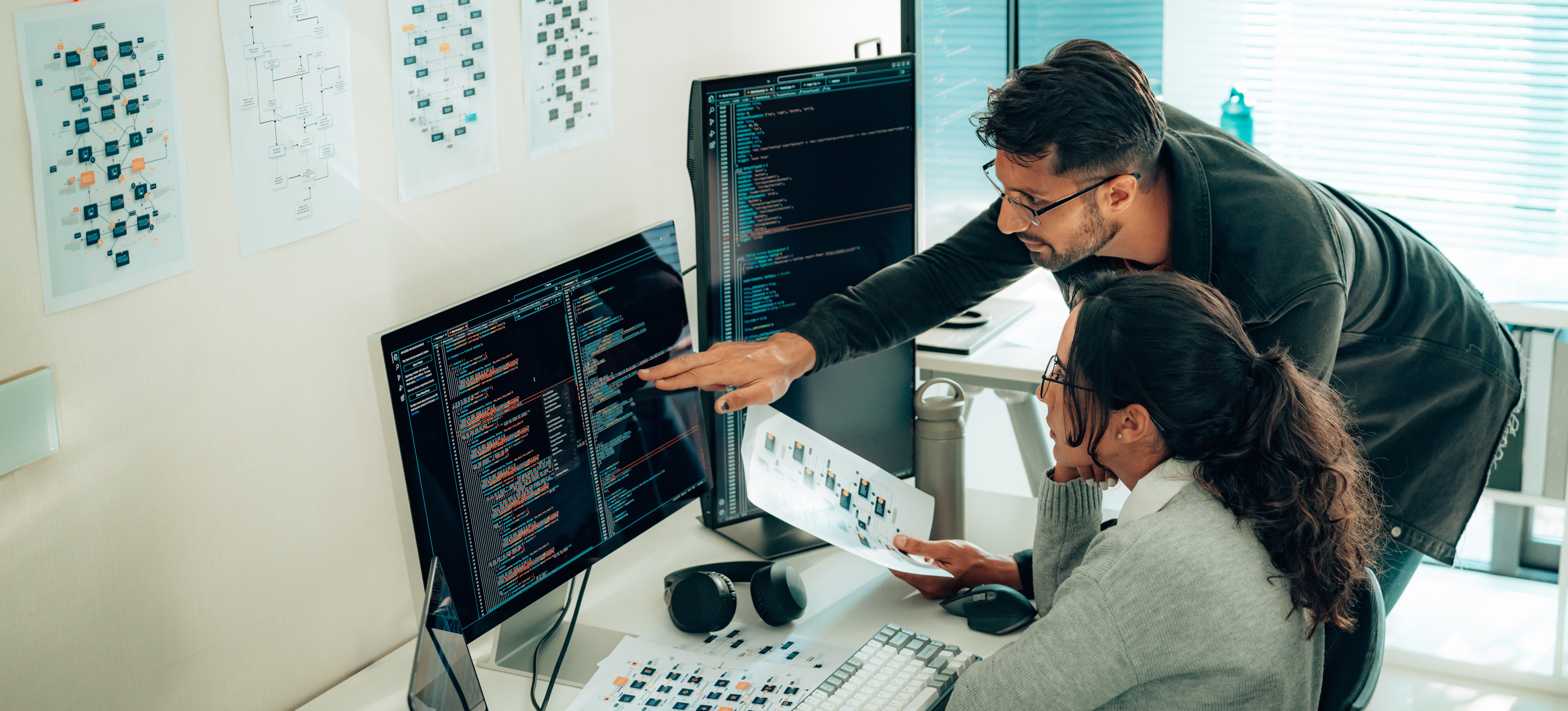 [Featured image]Two colleagues work on a computer while discussing data privacy vs. data protection.
