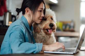 [Featured image] A woman sits at a laptop with her dog shopping online.
