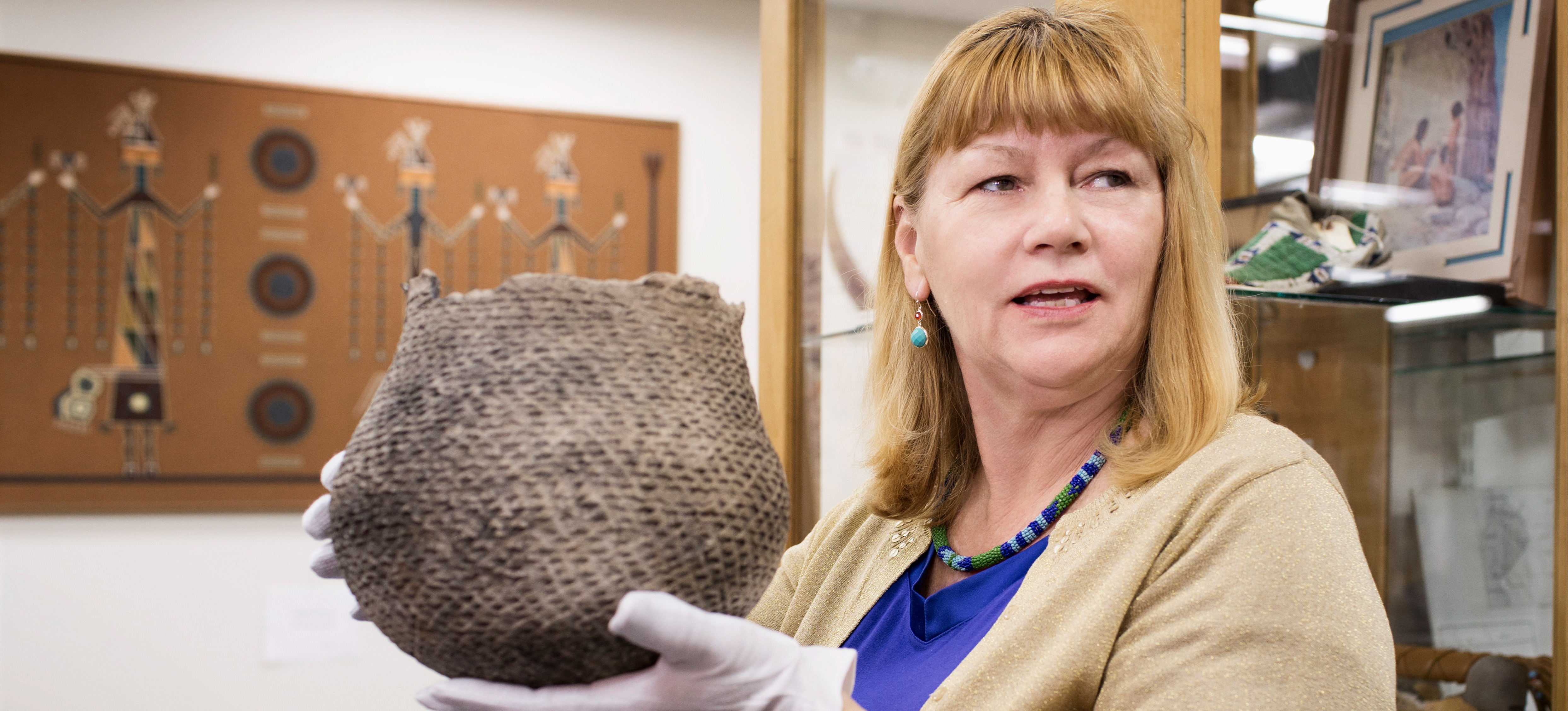 [Featured Image] A museum curator with a history degree wears gloves while holding an ancient artifact. 
