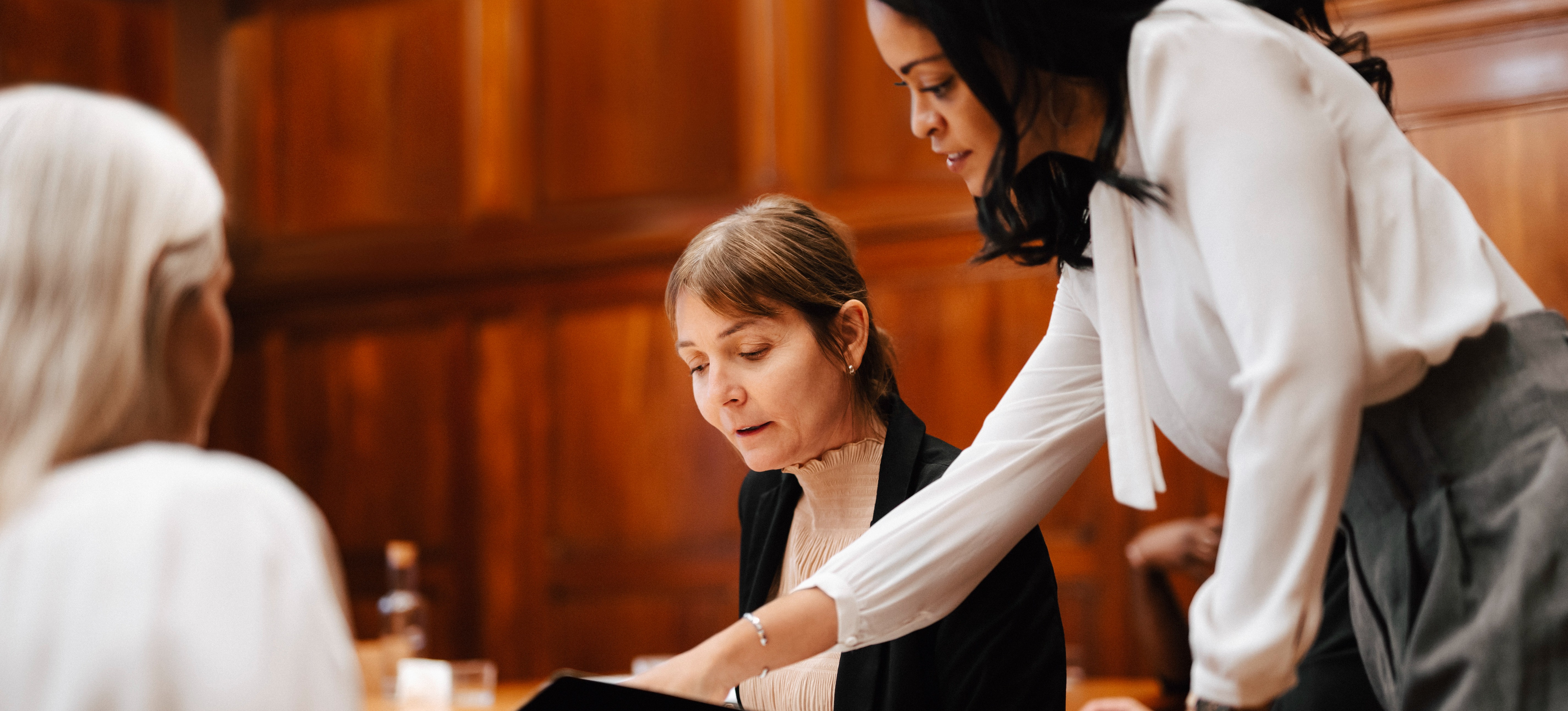[Featured Image] After learning how to prepare an income statement, an entrepreneur reviews the document with potential investors in a wood-paneled room.
