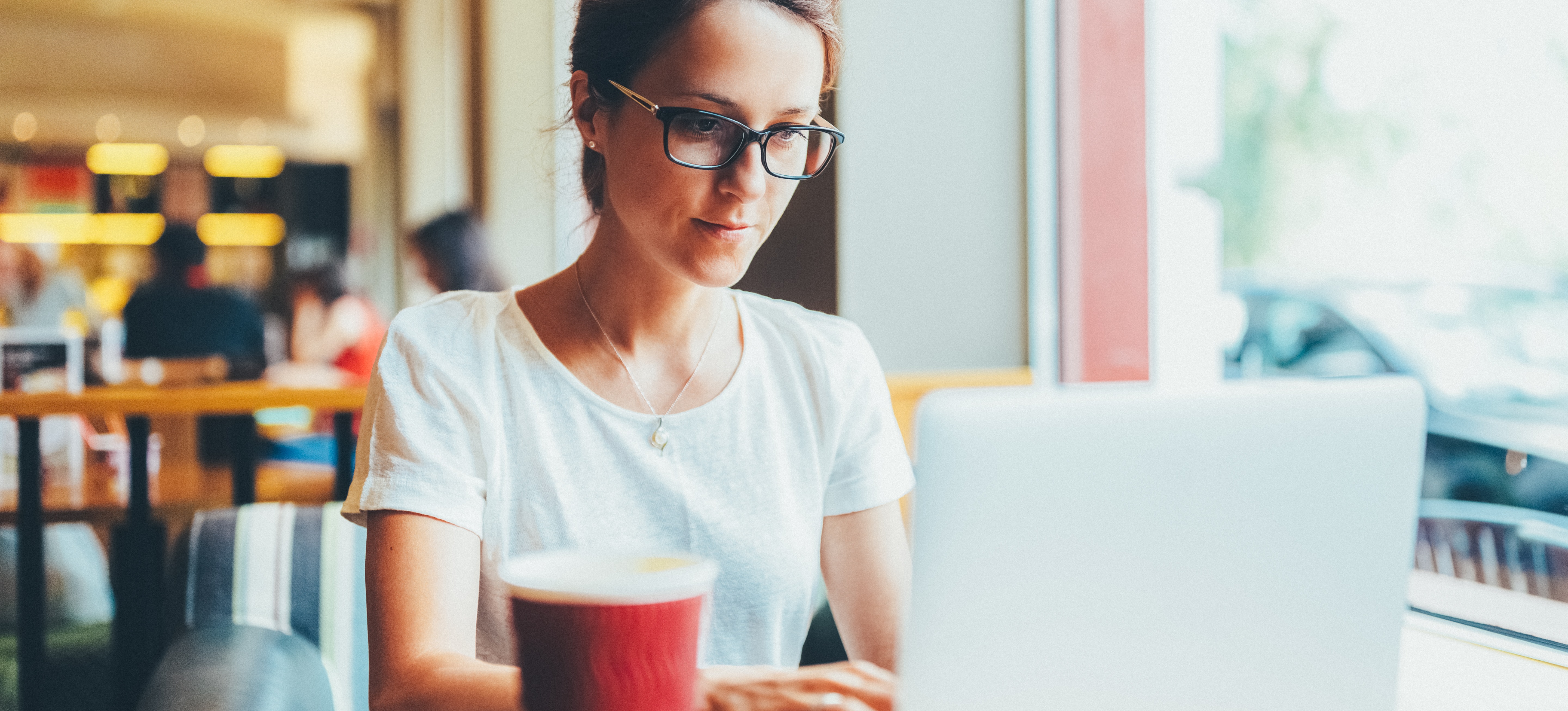 [Featured Image] A person is on their laptop in a cafe, working on a certification for email marketing.
