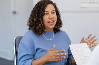 A woman is seen explaining an answer during a job interview.