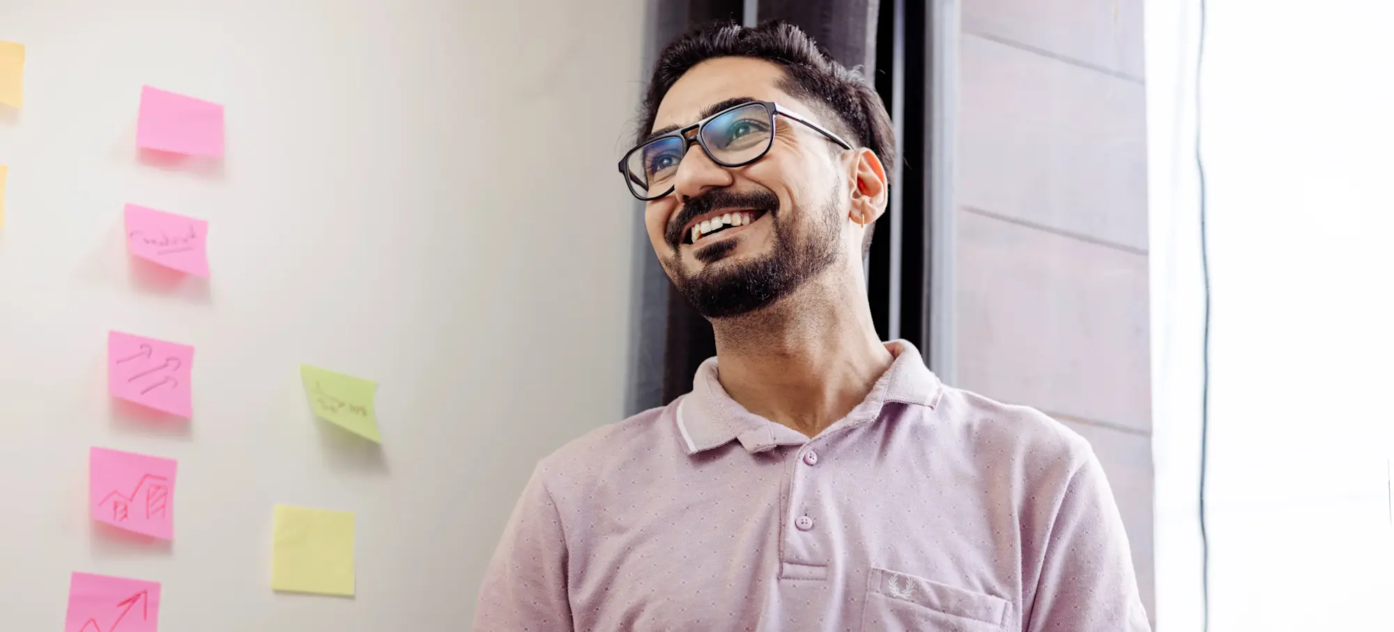 [Featured Image]: A man smiles as he leads a team developing a jobs to be done statement as part of the product development process.
