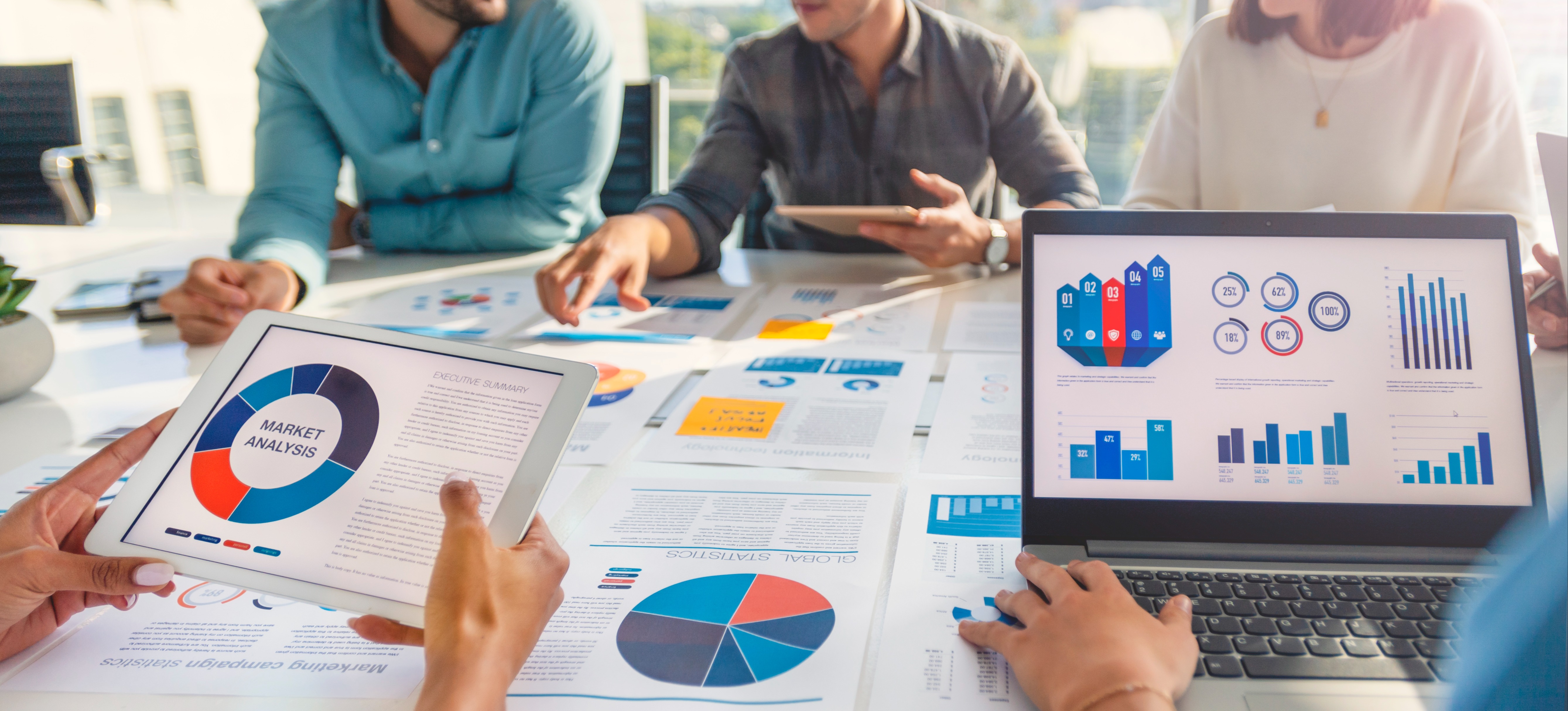 [Featured Image] A group of data analysts engaged in a discussion in a professional setting, reviewing graphs and charts displayed on both paper and a computer screen while comparing R and Tableau for data analysis and visualization.
