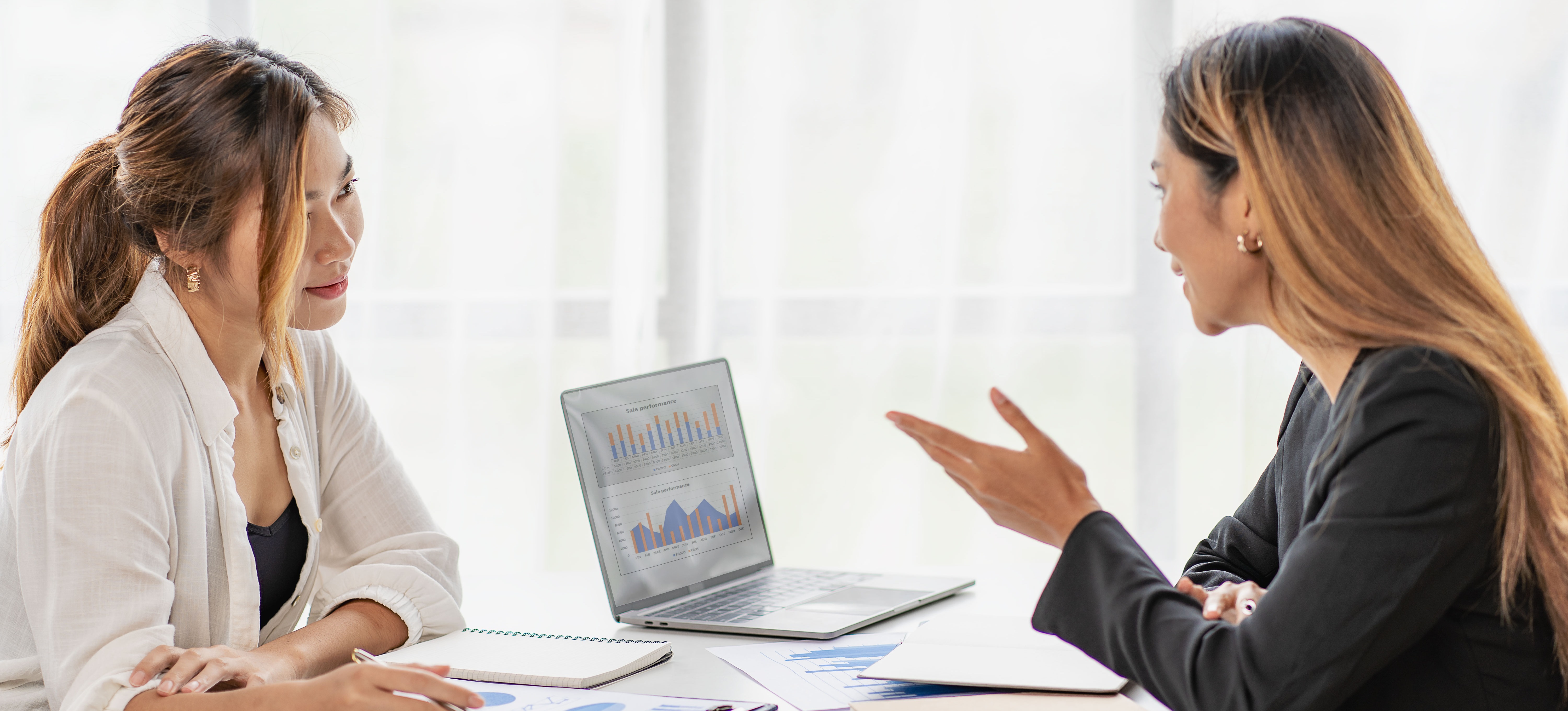 [Featured Image] A data engineer and a data scientist collaborate at a desk with a laptop, paperwork, and calculator. ﻿
