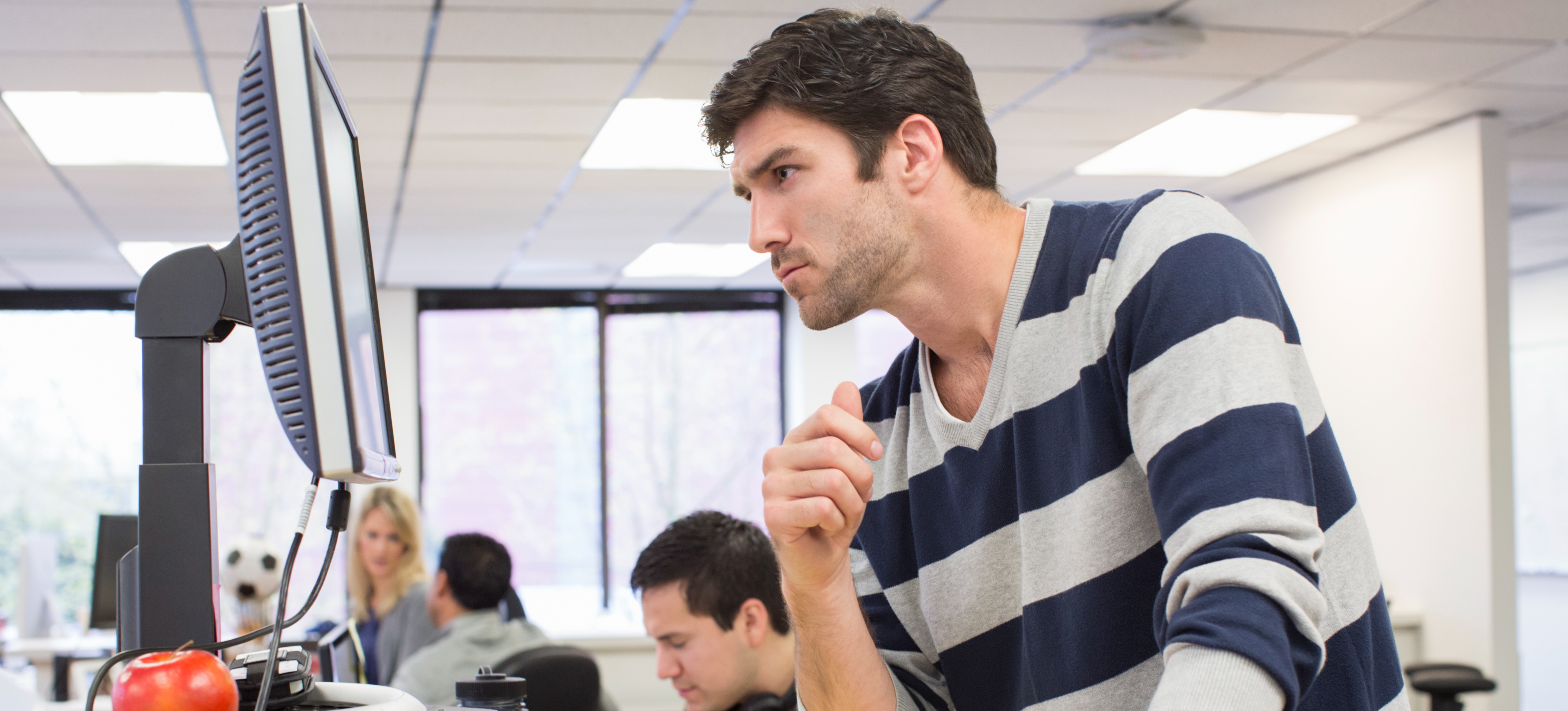[Featured Image] A network manager is at a computer in an office updating new software.