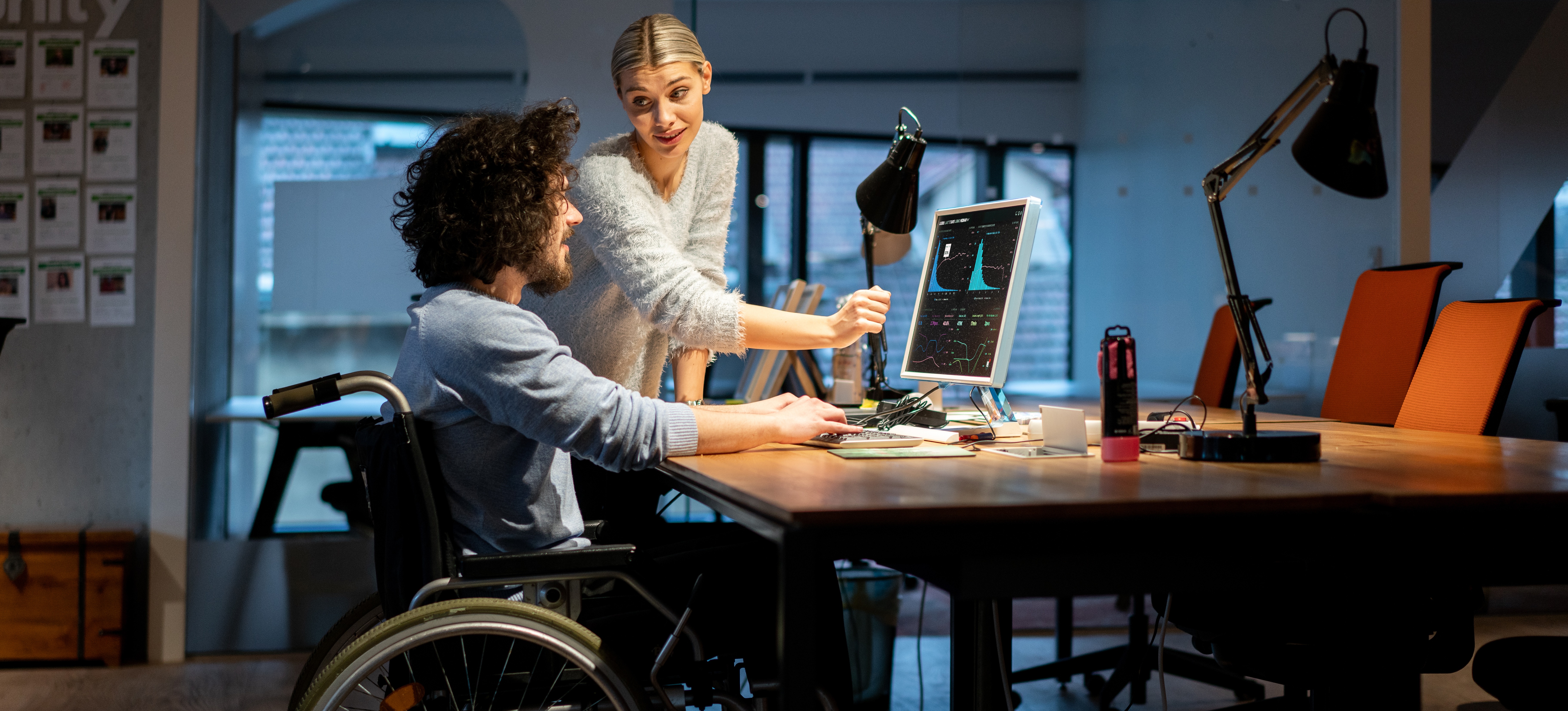 [Featured Image] A woman is discussing the crypto market cap with a man at a computer.