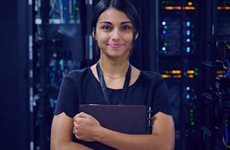 [Featured image] A cybersecurity analyst holds a notebook and stands in front of a room filled with servers.