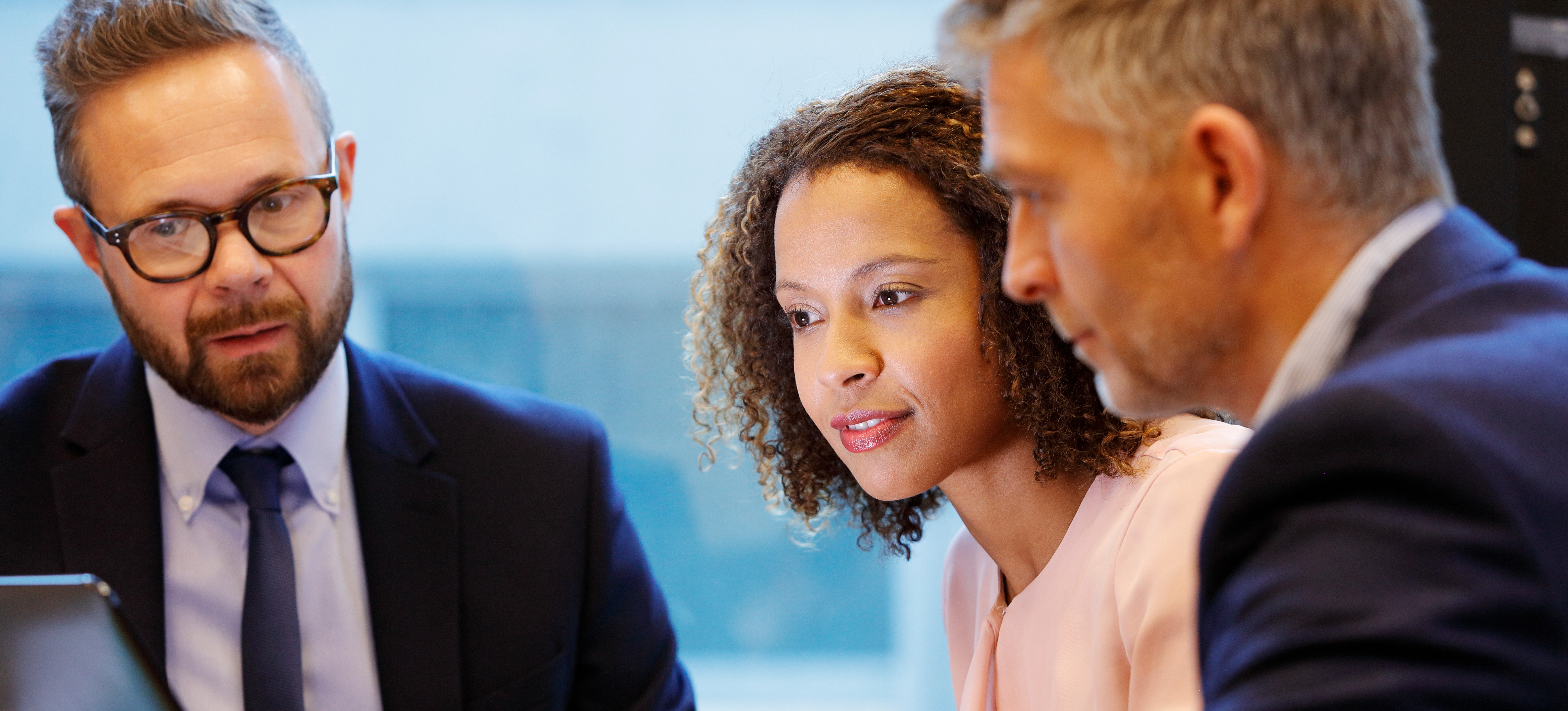 [Featured image] A professional trained in managerial accounting goes over data displayed on a laptop screen with two colleagues.
