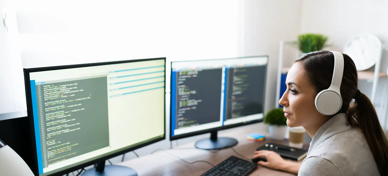 [Featured Image]:  A data manager who understands SQL and NoSQL is sitting at their desk, working on two desktop computers.