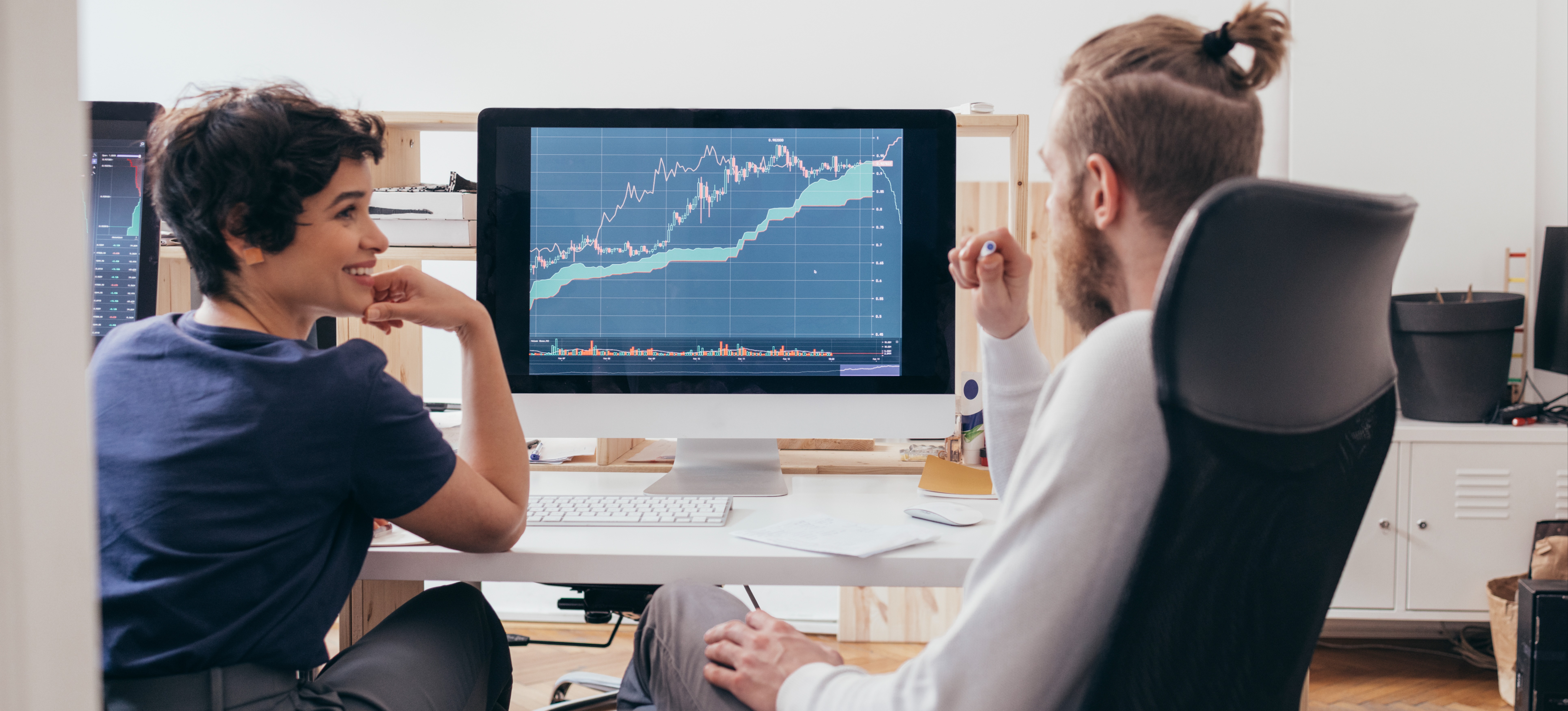 [Featured Image] Two financial analysts learned a programming language and are discussing how their new knowledge contributes to better analysis.
