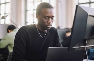 [Featured Image] A cloud security engineer is working on his cloud security certification while working on his computer.