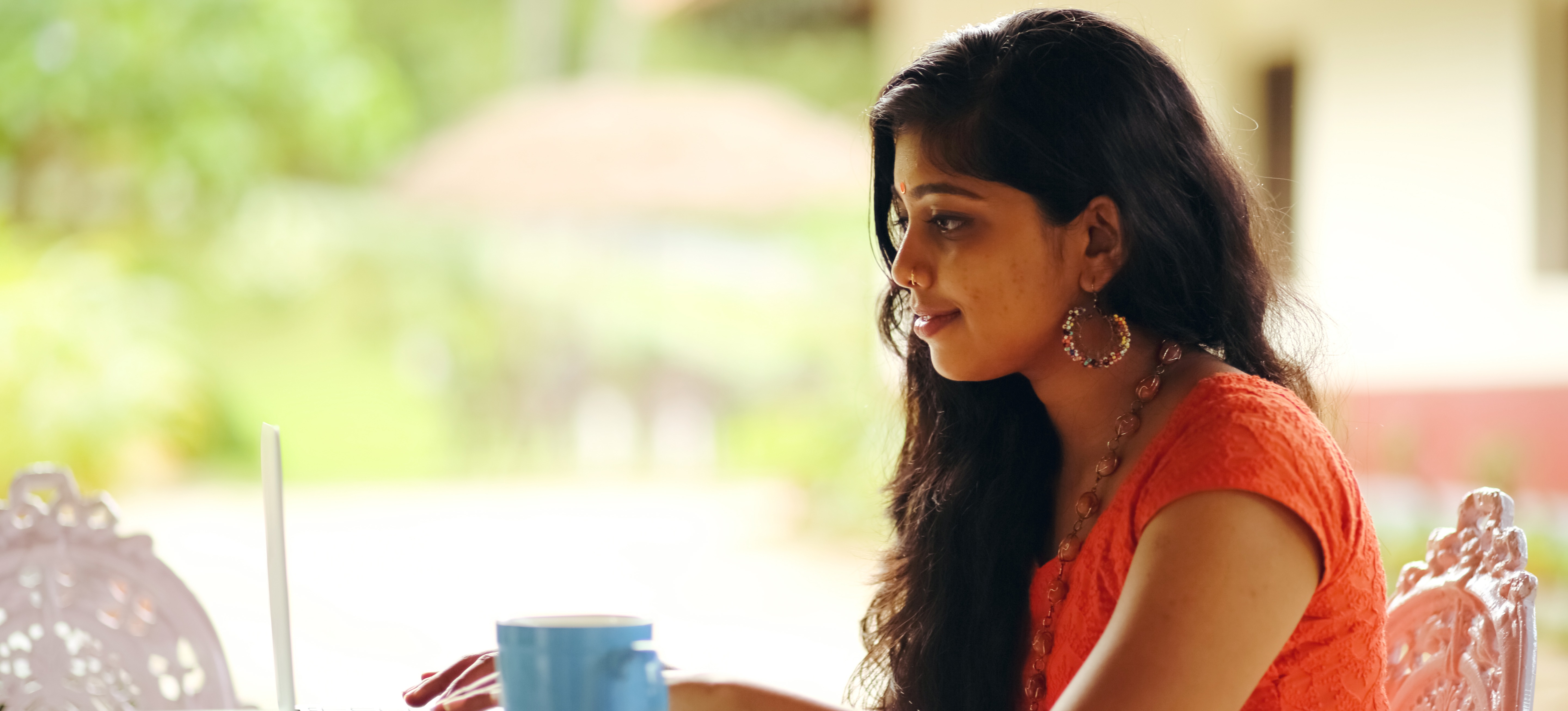 [Featured Image] A person sits at an outdoor table and uses a laptop to work one of many highest-paying remote jobs.

