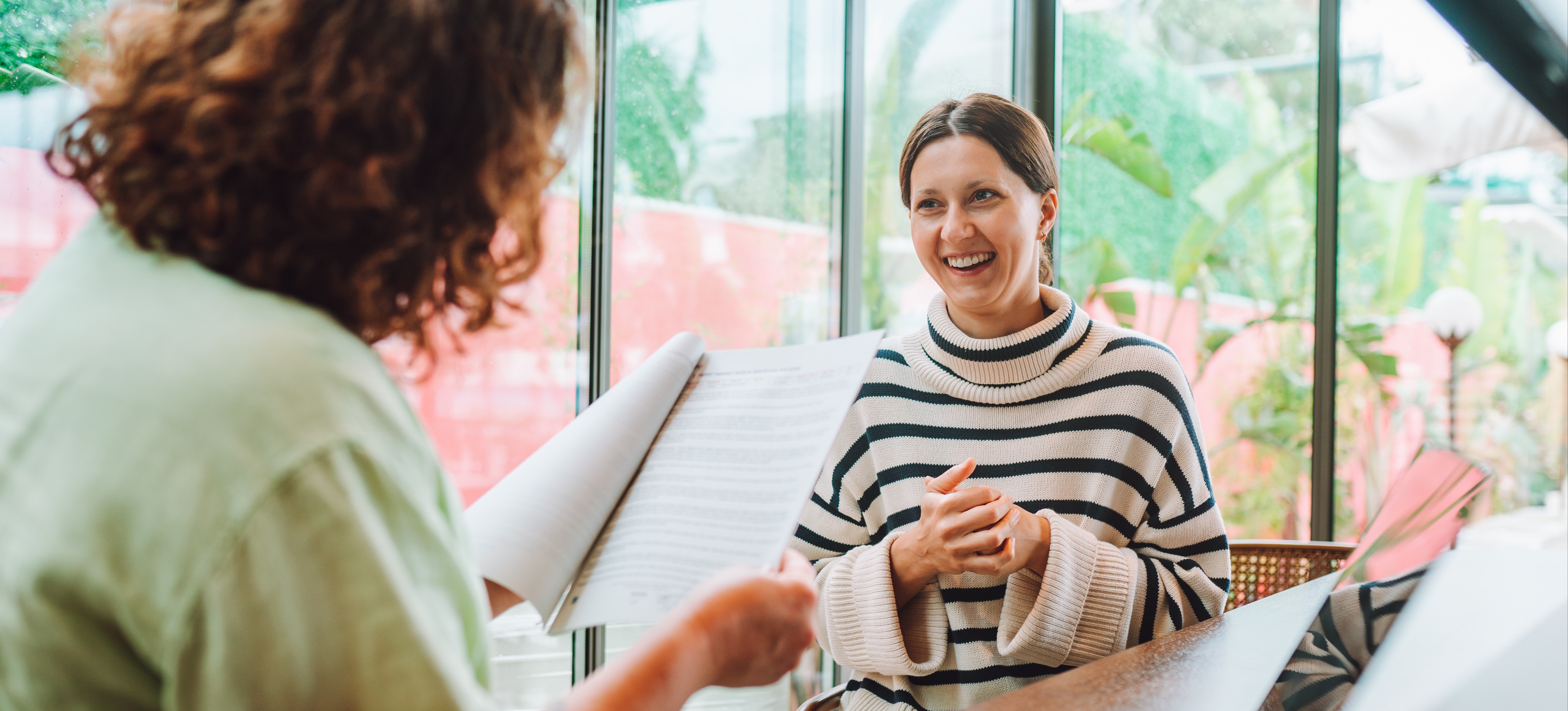 [Featured Image] A recruiter reviewing a candidate's resume during a job interview, discussing key questions for a network administrator role.
