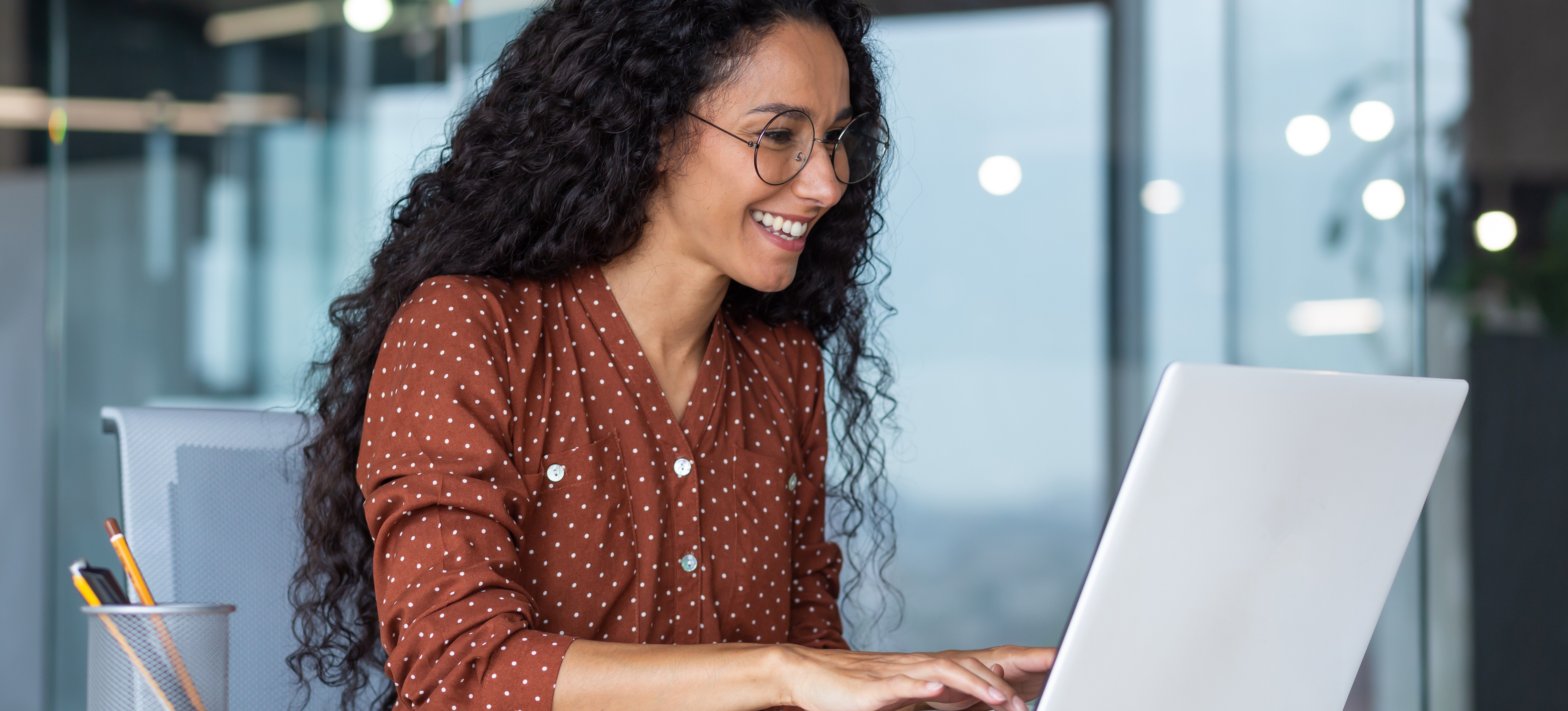 [Image en vedette] Un employé souriant est assis dans un bureau bien éclairé et utilise ChatGPT sur son ordinateur portable.
